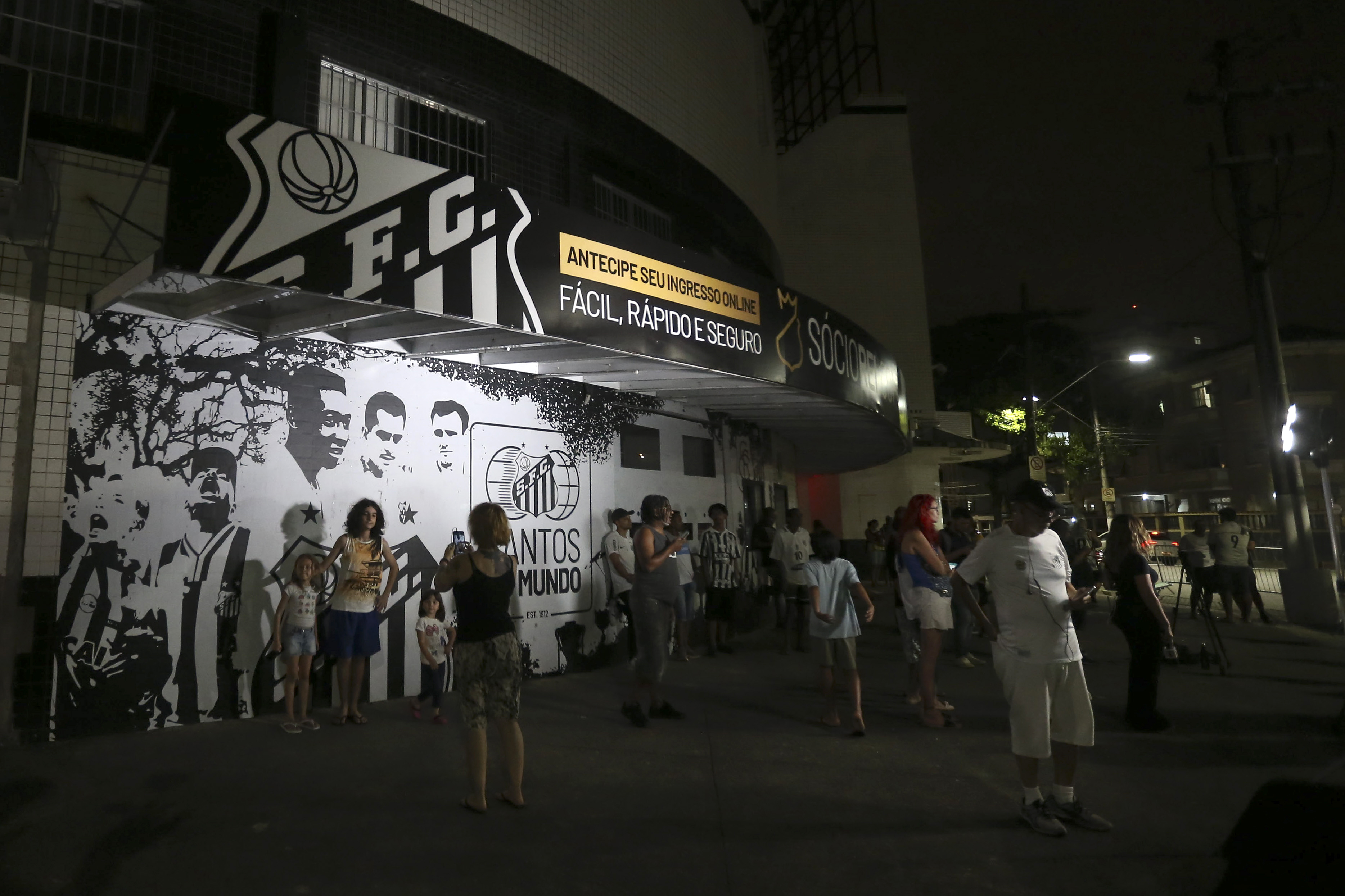 AME3233. SANTOS (BRASIL), 29/12/2022.- Aficionados del club Santos se concentran frente al estadio Urbano Caldeira en la Vila Belmiro hoy en la ciudad de Santos (Brasil). El mundo quedó conmocionado este jueves con el anuncio de la muerte, a los 82 años, de Edson Arantes do Nascimento 'Pelé', para muchos el rey del fútbol, un deporte en el que sus más emblemáticos representantes coincidieron en denominar "eterno" al máximo ídolo de los brasileños. EFE/ Guilherme Dionizio