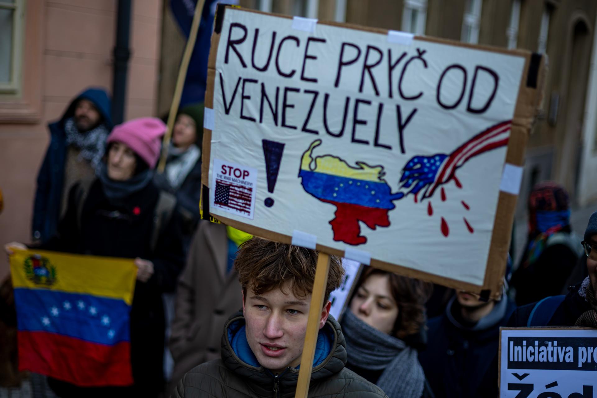 PRAGUE (Czech Republic), 04/01/2026.- A participant holds a placard 'Hands off Venezuela' as people protest against the US actions in Venezuela and reject regime change by military force as violation of international law, outside the US Embassy in Prague, Czech Republic, 04 January 2026. US President Donald Trump announced that US forces have successfully captured Venezuelan President Nicolas Maduro and his wife during a series of large-scale strikes on Caracas on 03 January 2026. (Protestas, República Checa, Praga) EFE/EPA/MARTIN DIVISEK