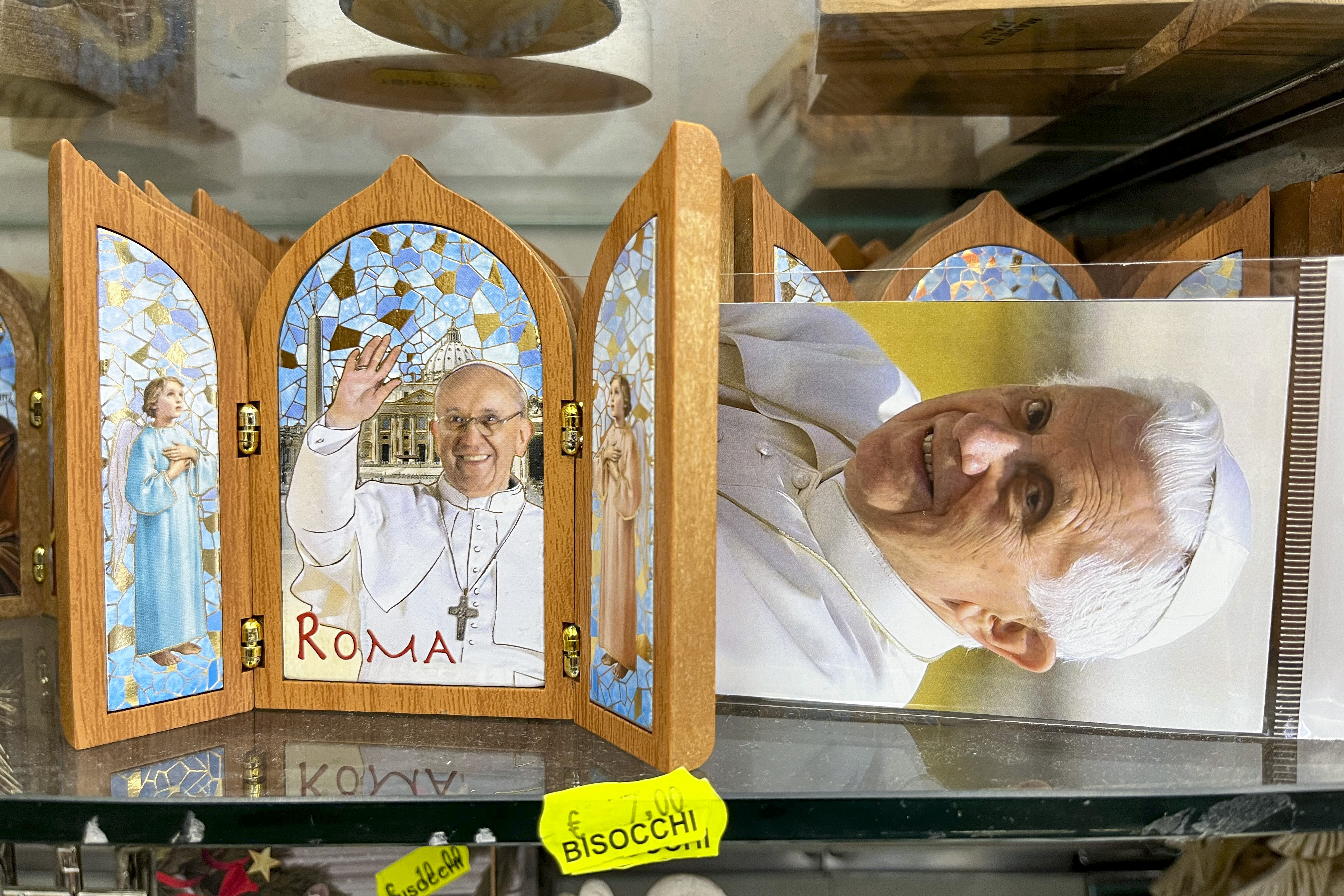GRAF1960. CIUDAD DEL VATICANO, 03/01/2023.- Algunos suvenires que retratan al papa emérito Benedicto XVI en las tiendas que rodean el Vaticano. Las leyes del libre mercado afectan hasta a las cuestiones más sacras y cientos de tiendas hacen el agosto al calor del Vaticano vendiendo recuerdos y minucias con cada evento pontificio. Sin embargo, la muerte de Benedicto XVI pasa sin pena ni gloria por sus estanterías. Es el papa sin suvenires. EFE/ Gonzalo Sánchez