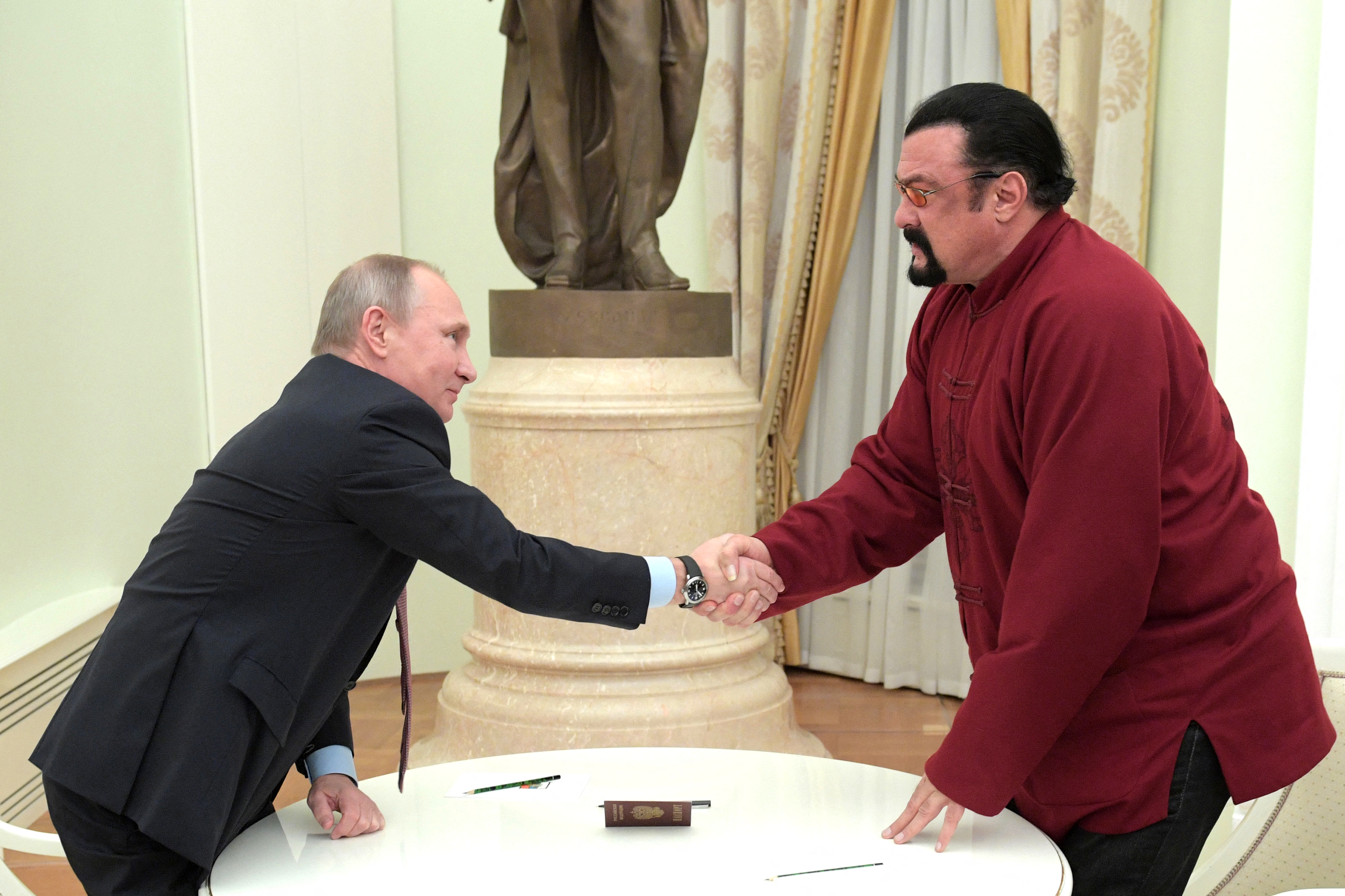 En esta foto de archivo tomada el 25 de noviembre de 2016, el presidente ruso, Vladímir Putin (izq.), estrecha la mano del héroe de acción estadounidense Steven Seagal tras entregarle un pasaporte ruso durante una reunión en el Kremlin en Moscú.
