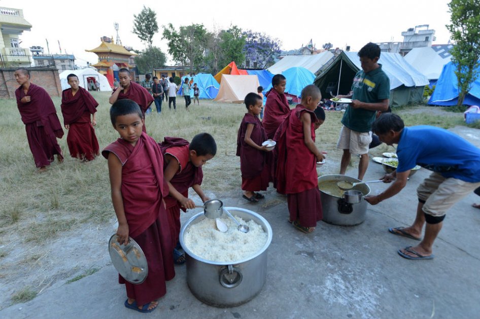 Jóvenes monjes budistas de Nepal hacen cola para recibir comida en un campamento para los sobrevivientes del terremoto en Katmandú. La destrucción de casi medio millón de casas ha dejado a miles de personas sin agua ni comida. /AFP