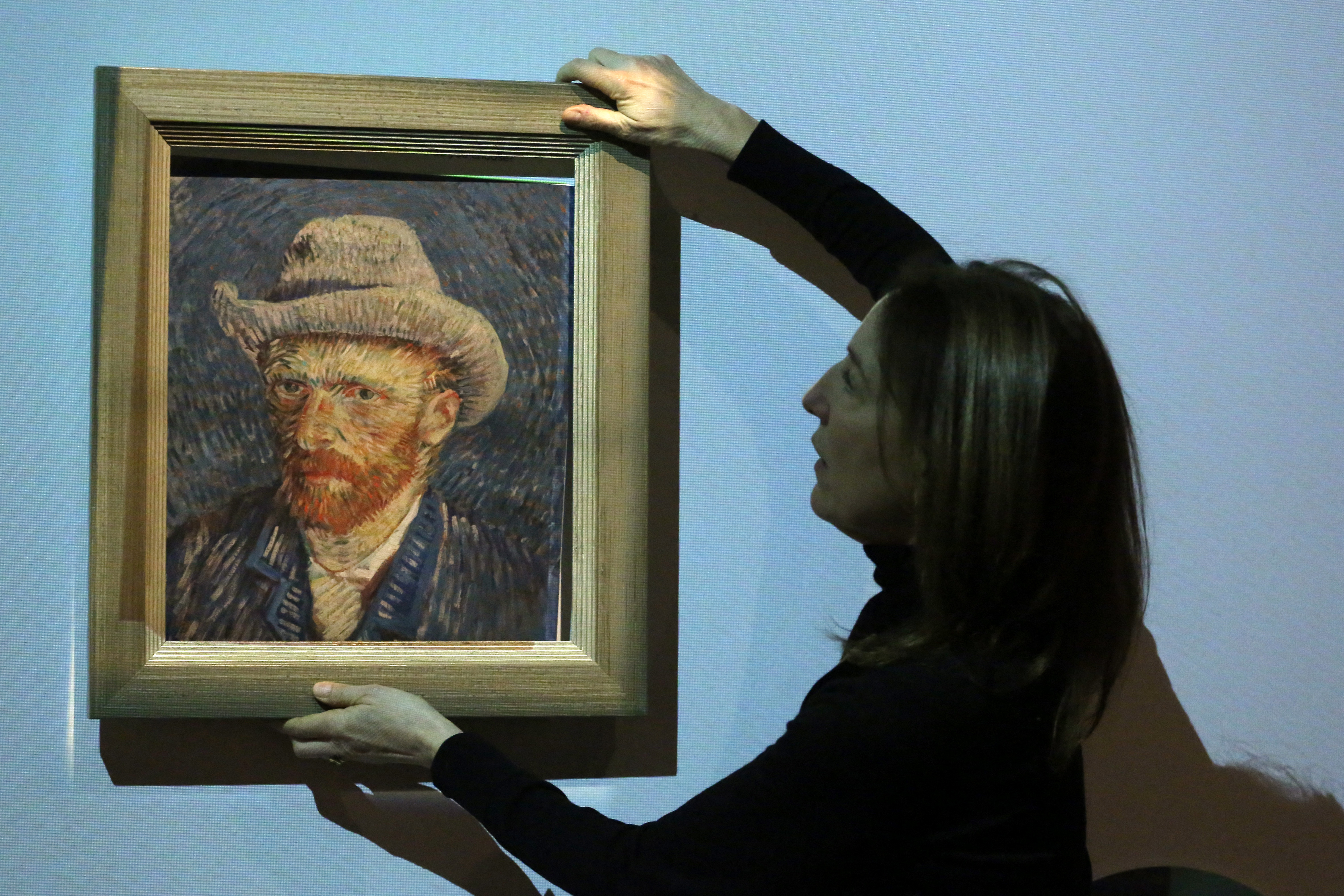 (FILES) Emilie Gordenker, director of the Van Gogh Museum, removes the frame of a reproduction of the painting "Self-Portrait with Grey Felt Hat" by Vincent Van Gogh as part of an interactive section of the exhibition "Choosing Vincent - Portrait of a family history" at Van Gogh Museum in Amsterdam, on February 8, 2023.