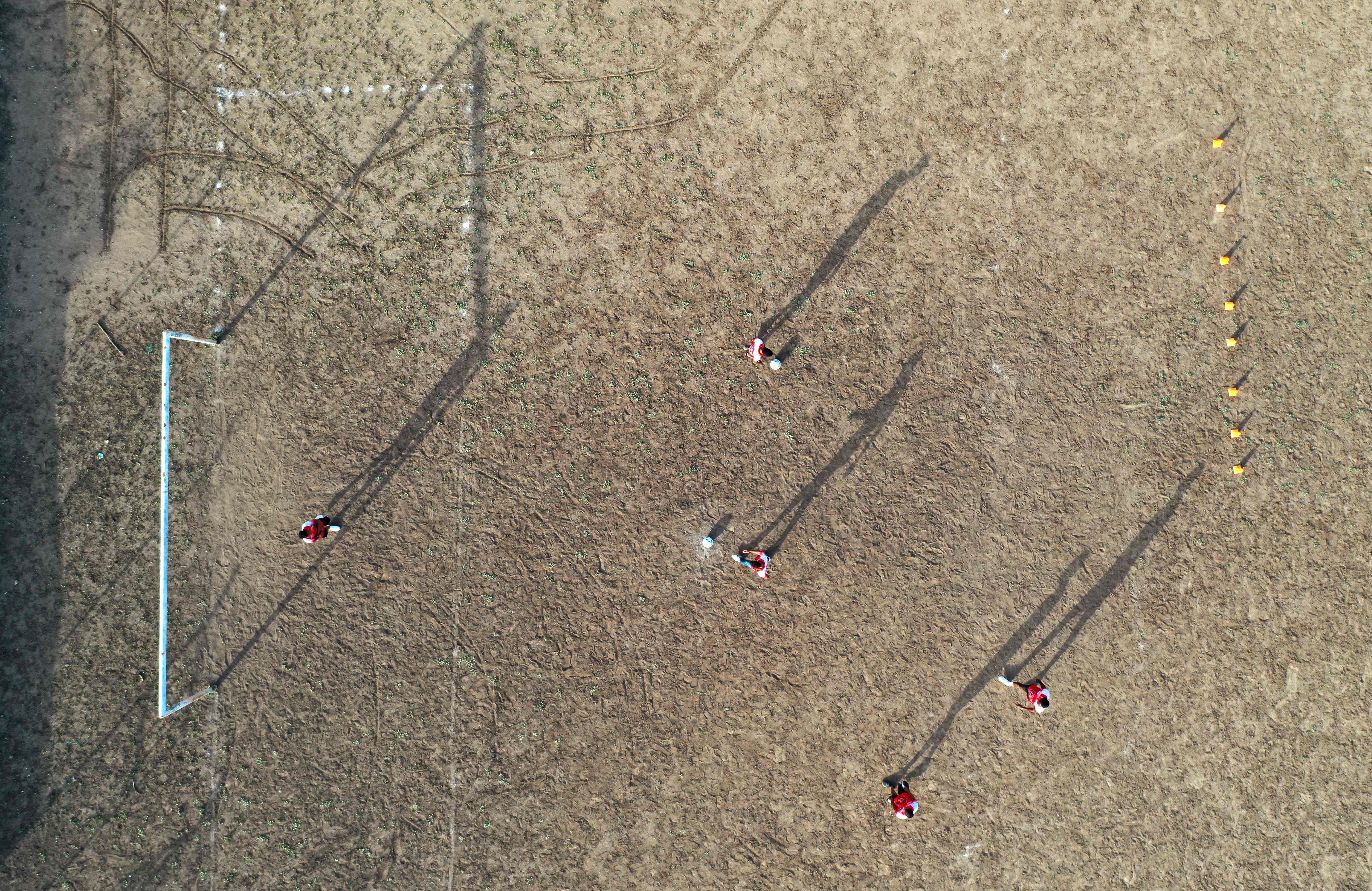 Vista aérea de niños jugando al fútbol en un campo polvoriento, en el que Luis Díaz empezó a llenarse de gloria.