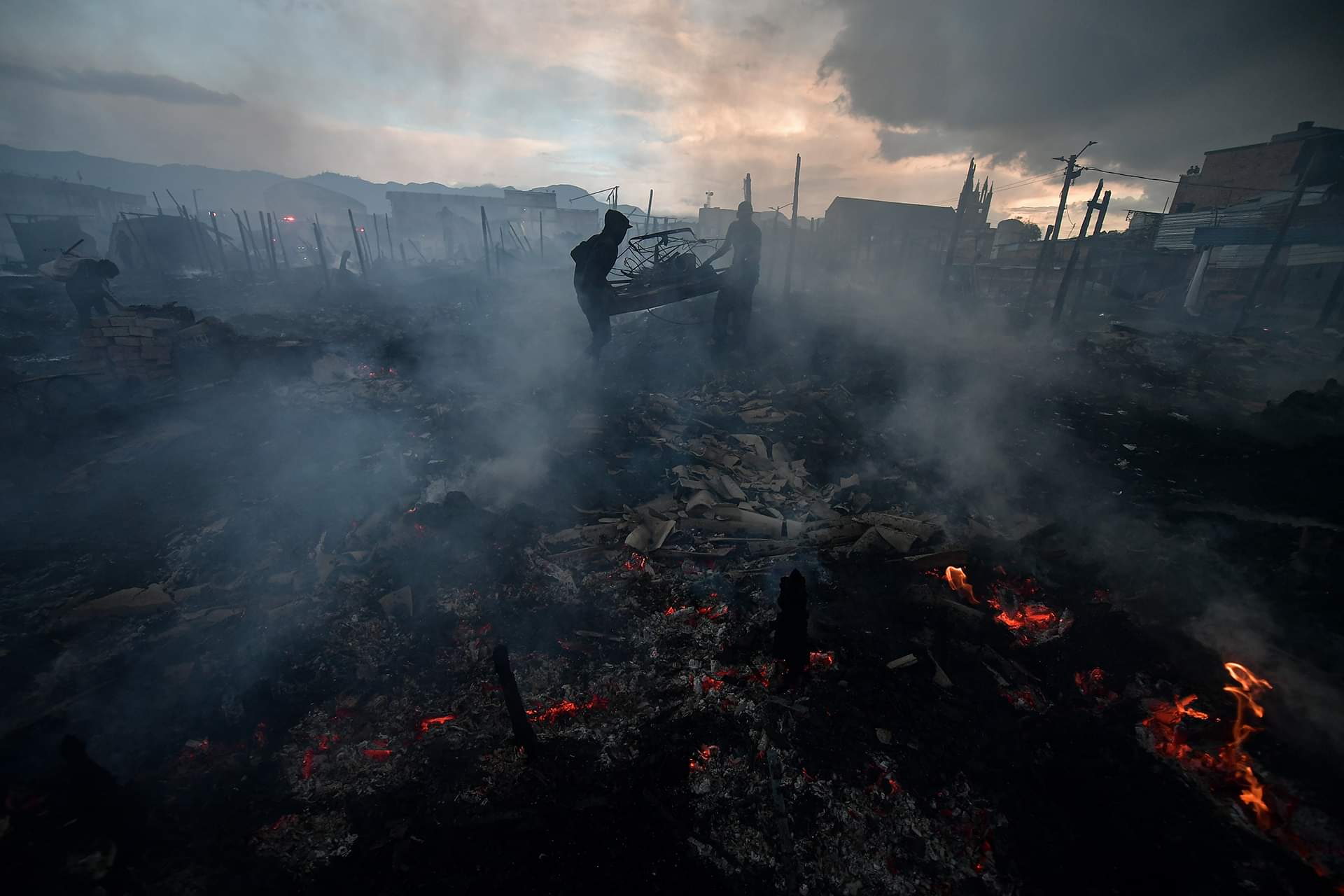 Dos personas intentan sacar parte de los escombros que dejó el incendio