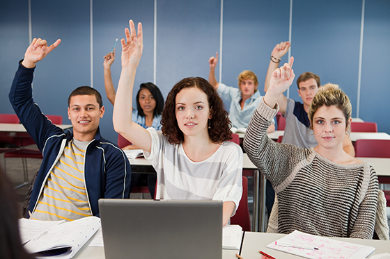 University students holding up hands in class