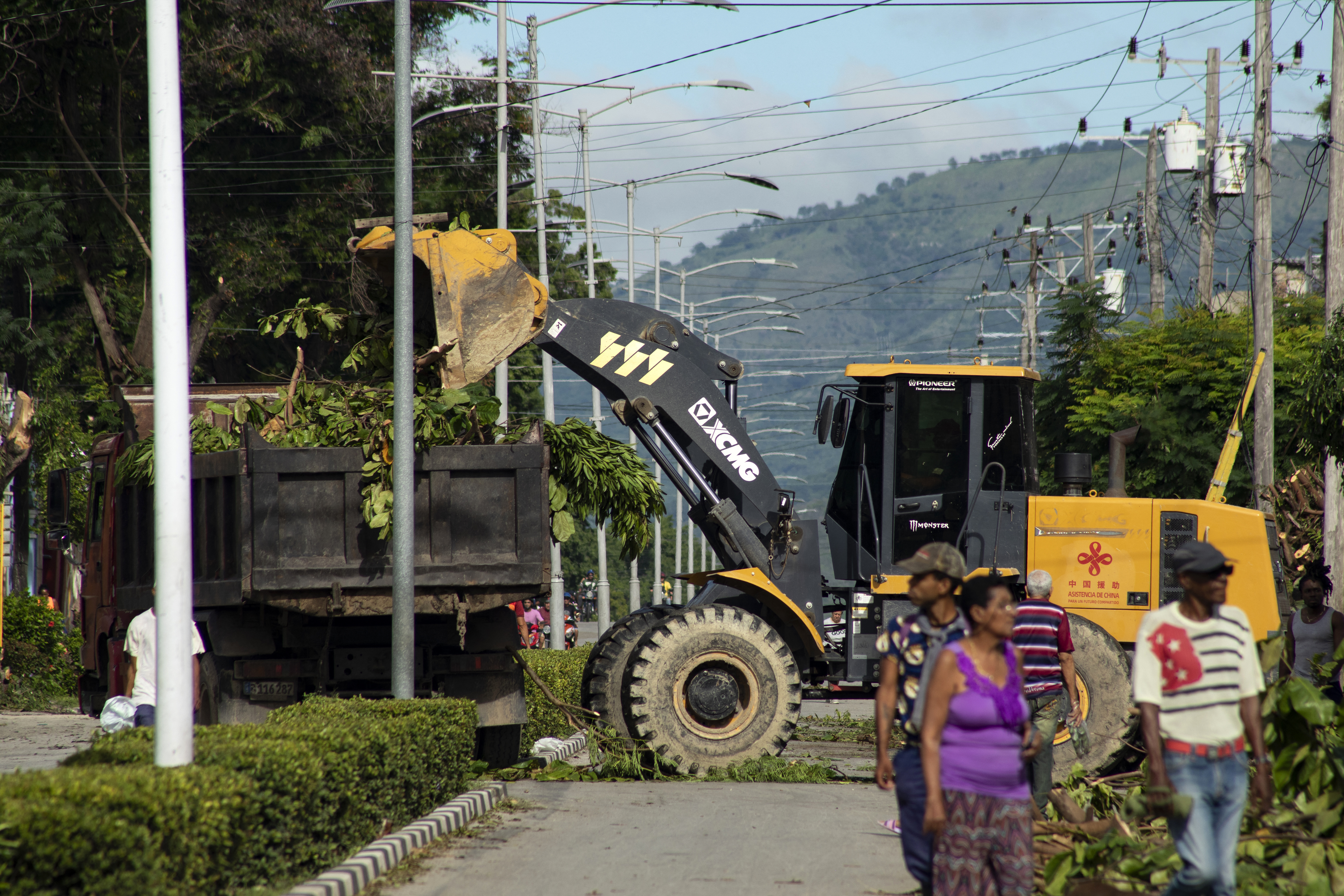 A tractor loads pruned tree branches onto a truck ahead of the arrival of Tropical Storm Melissa in Santiago de Cuba on October 25, 2025.