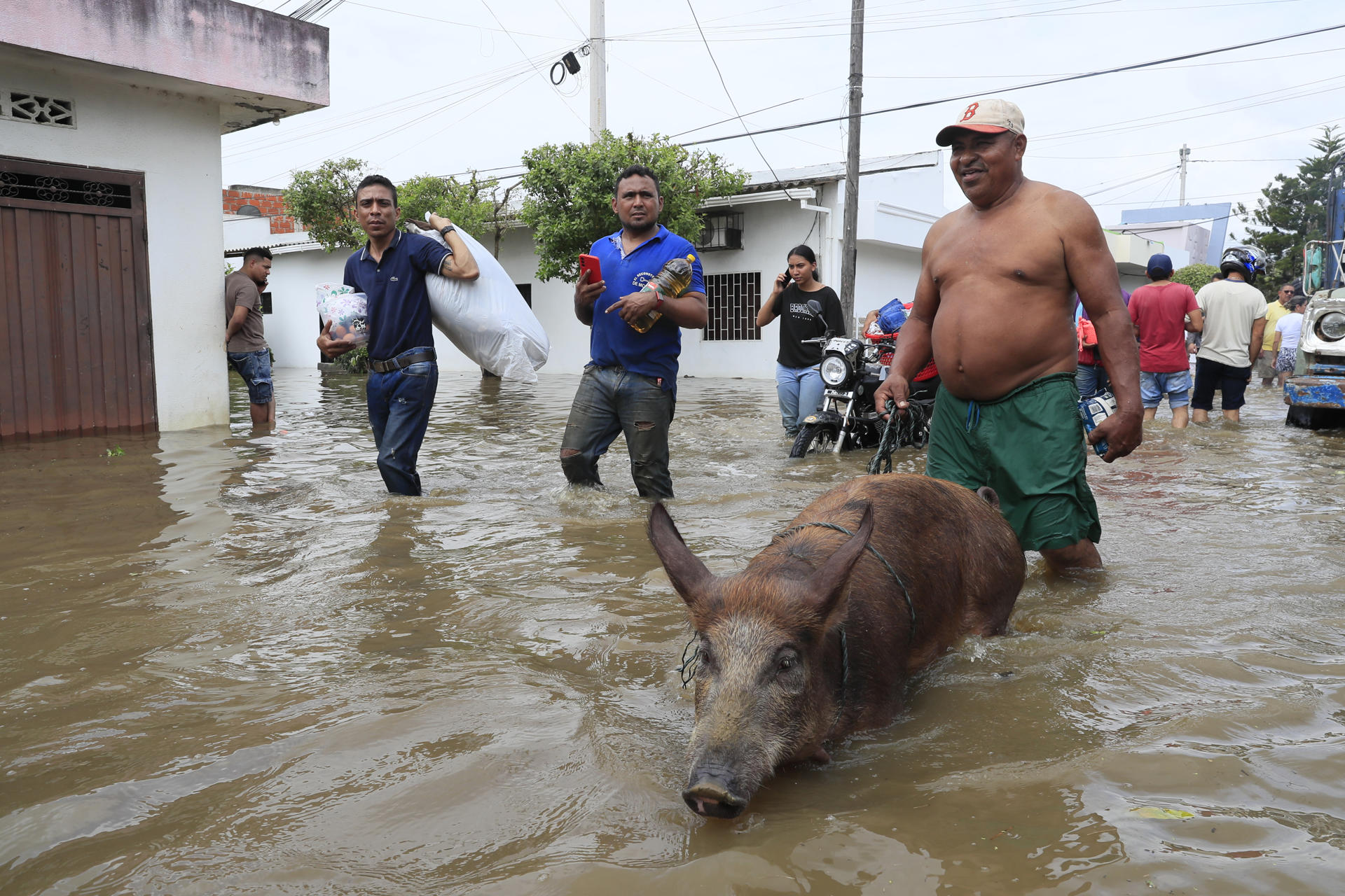 AME2911. MONTERÍA (COLOMBIA), 07/02/2026.- Personas caminan junto a un animal por una calle inundada este sábado, luego de una nueva creciente del río Sinú que afectó el barrio El Dorado en Montería (Colombia). El presidente colombiano Gustavo Petro anunció que decretará un nueva emergencia social, económica y ambiental para hacerle frente a las inundaciones que afectan gran parte de Colombia. EFE/ Carlos Ortega