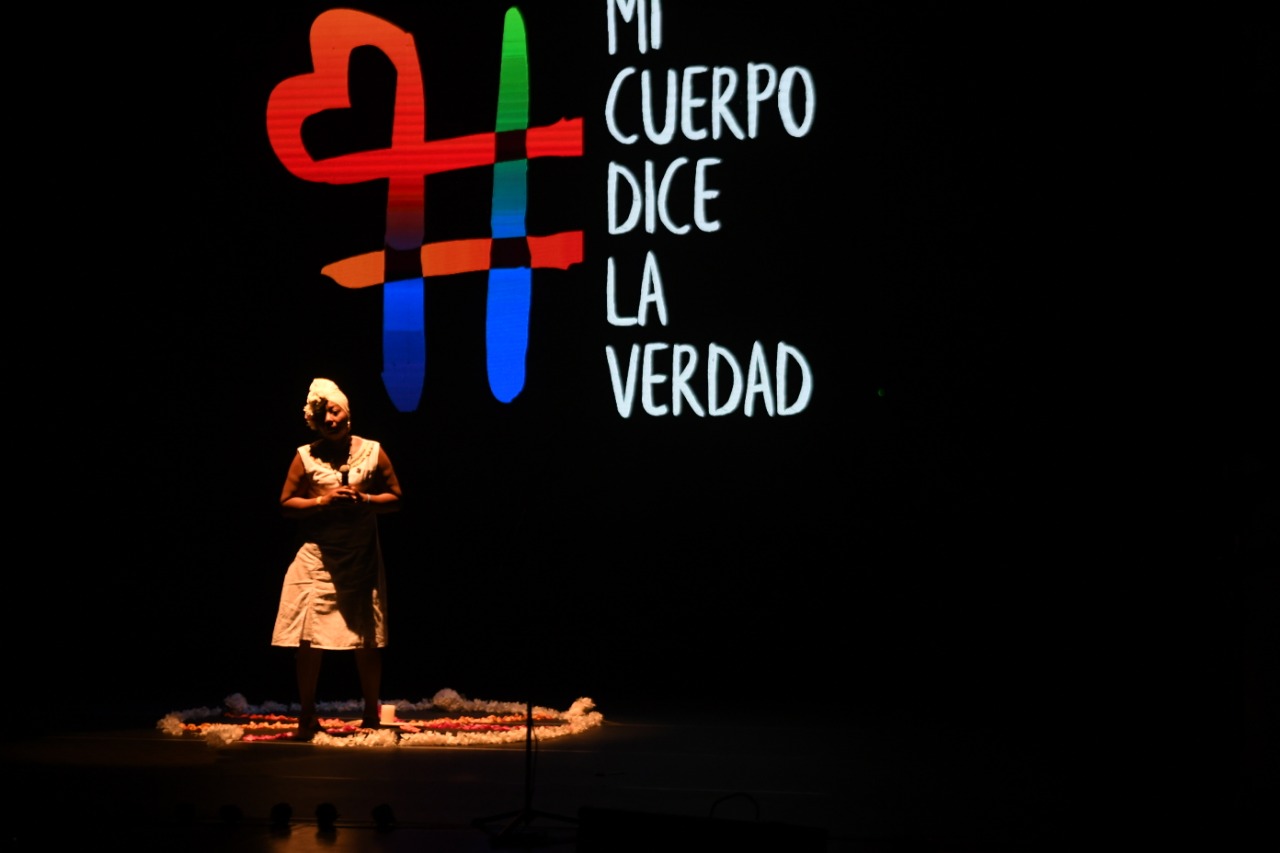 Y todas las victimizaciones fueron distintas, pero existen patrones que ya se han empezado a conocer. Por ejemplo, la violencia que quería asesinar a las mujeres trans por transgredir los roles de género. Pero siguen vivas, se pusieron trajes brillantes y preciosos, tacones y tocados para gritar: ¡Estamos vivas, estamos vivas, estamos vivas! Y entregar la bandera trans al padre Francisco de Roux, presidente de la Comisión.