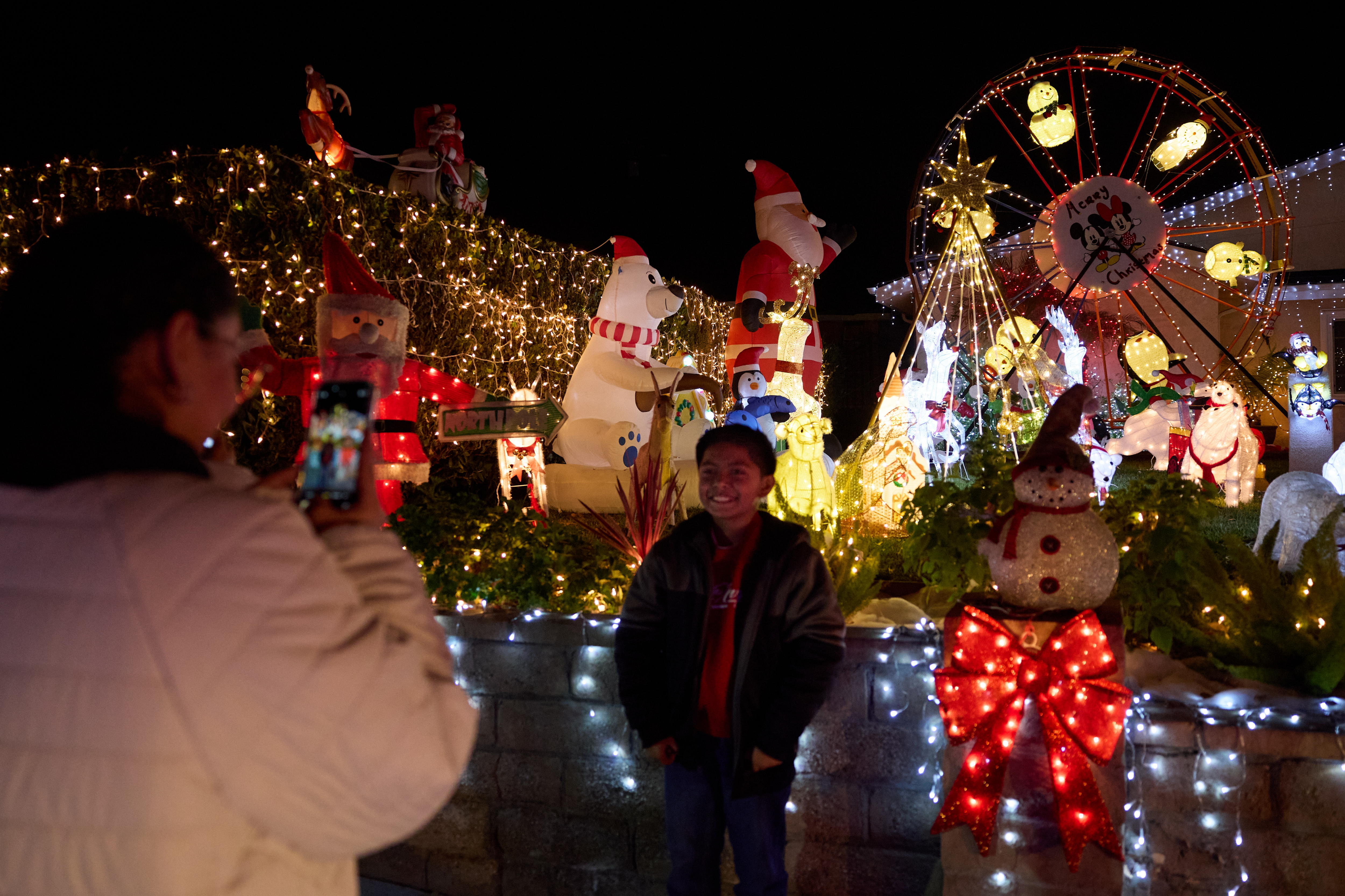 Pasadena (United States), 14/12/2024.- A person takes a photo of their son in front of a house that is decorated with lights for the holidays in the Hastings Ranch neighborhood of Pasadena, California, USA, 13 December 2024. The Hastings Ranch neighborhood has been doing elaborate displays of holiday lights for over 70 years. EFE/EPA/ALLISON DINNER