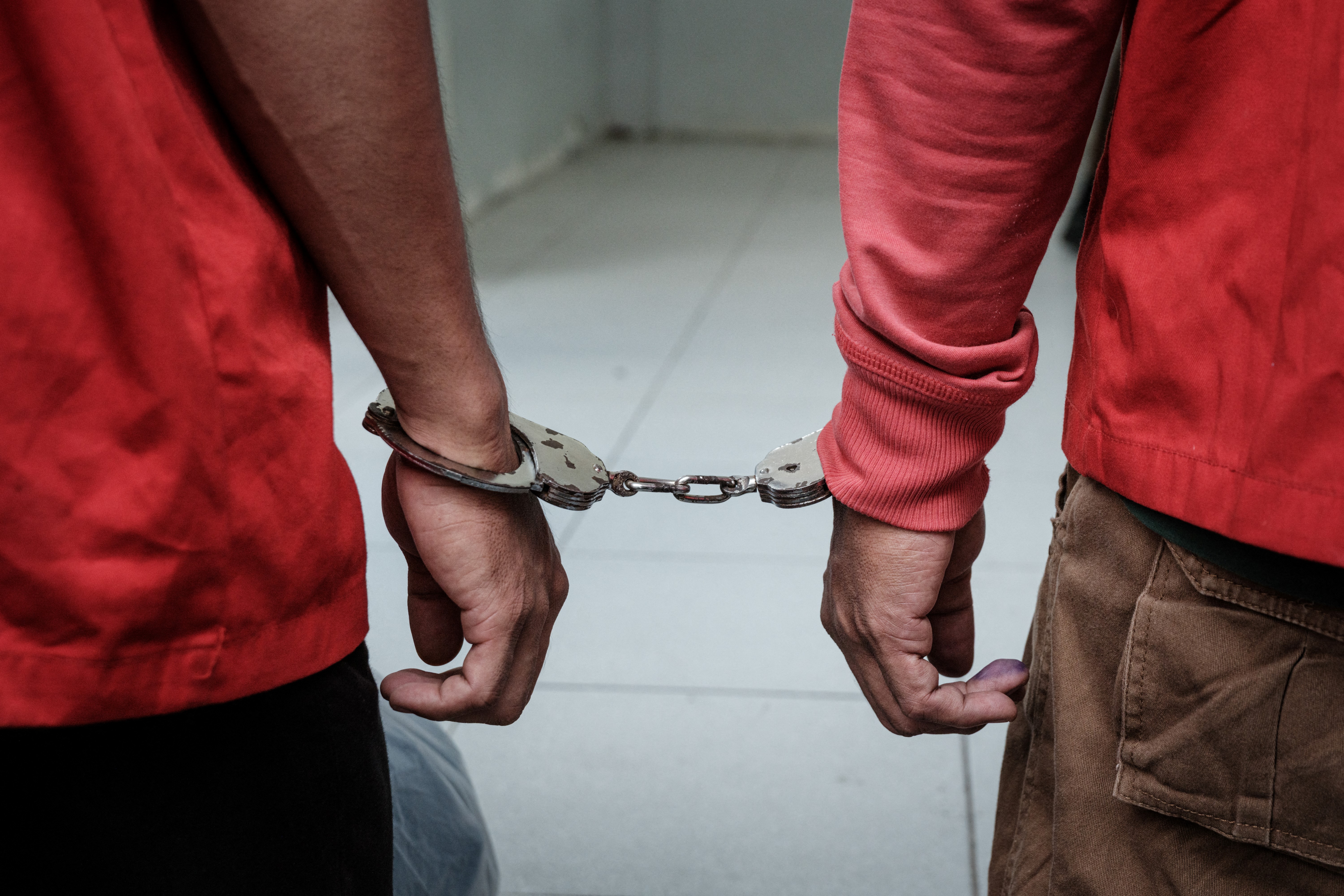A man (L), found guilty of sexual relations with another man under the strict Islamic sharia law, is handcuffed as he is being escorted to be publicly flogged in Banda Aceh on February 27, 2025. (Photo by YASUYOSHI CHIBA / AFP)