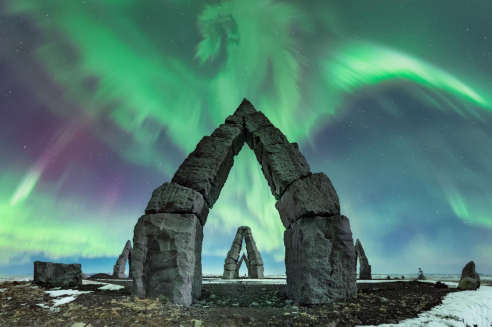 "Este panorama de auroras, que parece un gran dragón sobre las pirámides de roca, fue el resultado de una tormenta geomagnética (nivel G2) generada por una eyección de masa coronal ese mismo día. El resultado fueron intensas auroras rojizo-verdosas durante toda la noche. La ubicación de la foto es el Arctic Henge, que tiene un rico significado cultural para los islandeses, y fue el único lugar de Islandia con cielos despejados esa noche".