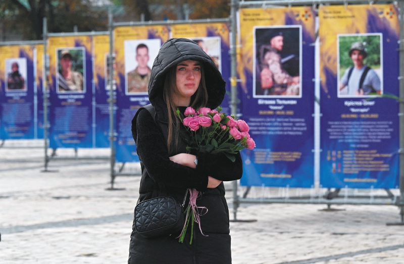 Una joven lloraba mientras caminaba entre retratos de militares muertos durante la inauguración de la exposición "Regimiento Azov - Ángeles de Mariupol", en el centro de Kiev, en conmemoración al Día de los Defensores de Ucrania, el 14 de octubre de 2022. 