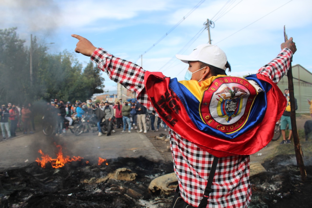 Un hombre de espaldas con una bandera de colombia en los hombros