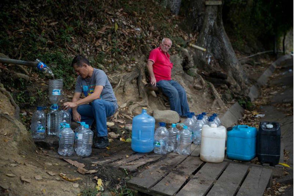 Fotografía del 9 de mayo del 2018, donde se observa a un grupo de personas recoger agua de una montaña junto a una autopista, en Caracas (Venezuela).  / EFE/Miguel Gutiérrez