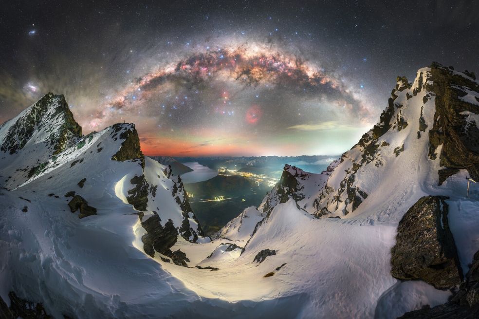 La foto de Tom Rae muestra el arco invernal de la Vía Láctea que se alza sobre la escarpada cordillera Remarkables, en los Alpes del Sur, mientras que las luces de Queenstown, Nueva Zelanda, brillan muy abajo.