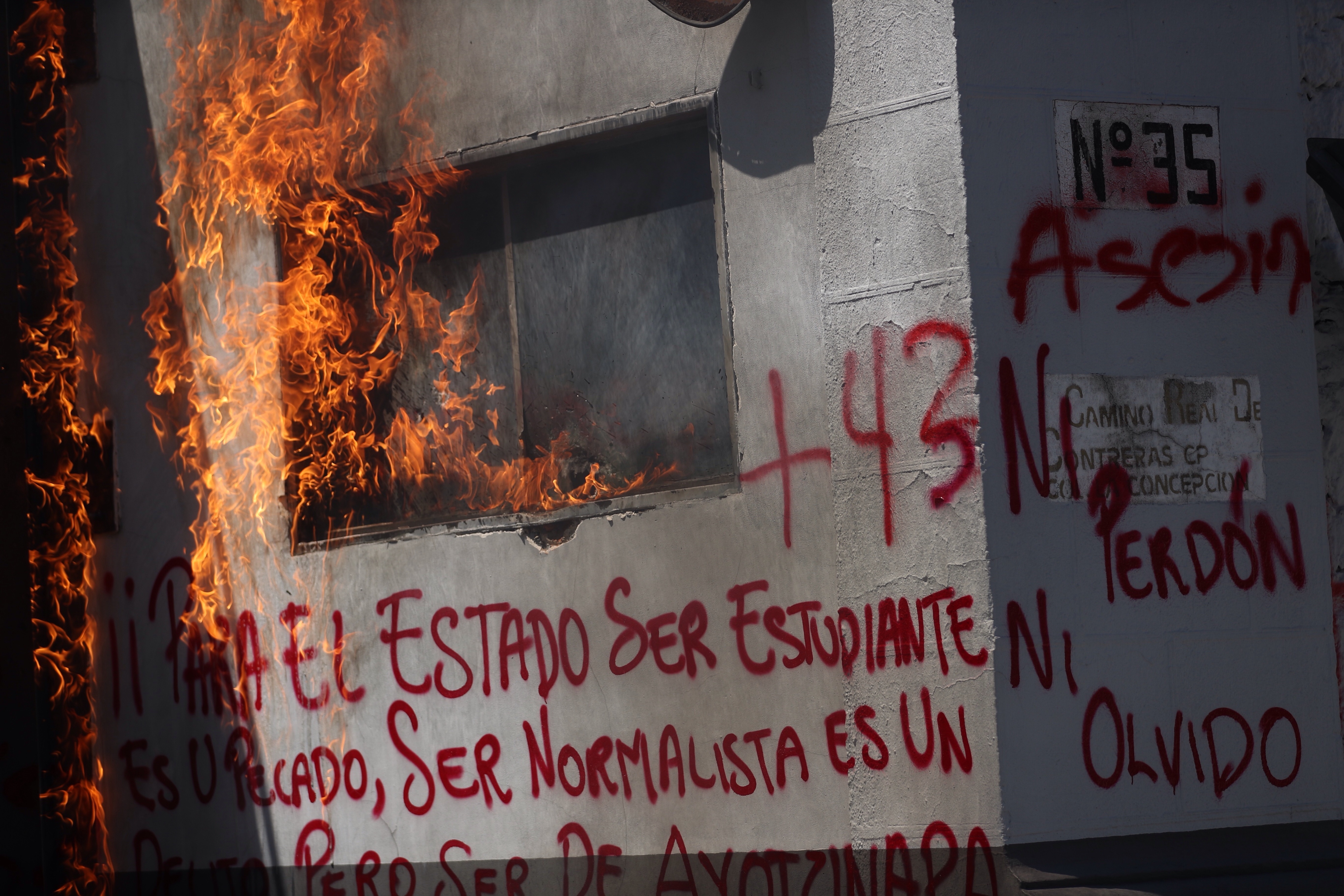 MEX6411. CIUDAD DE MÉXICO (MÉXICO), 25/09/2023.- Vista de un edificio en llamas y con mensajes durante una manifestación de estudiantes frente a las instalaciones del Centro de Investigación y Seguridad Nacional (CISEN) para exigir justicia por los 43 normalistas desaparecidos de Ayotzinapa, hoy en Ciudad de México (México). Compañeros de escuelas rurales y padres de los 43 estudiantes de Ayotzinapa desaparecidos en 2014 protestaron este lunes frente a las instalaciones del Centro de Investigación y Seguridad Nacional (Cisen) -ahora Centro Nacional de Inteligencia- ubicadas en la Ciudad de México, donde exigieron la entrega por parte del Ejército de documentos cruciales para dar con el paradero de los jóvenes. EFE/Sáshenka Gutiérrez