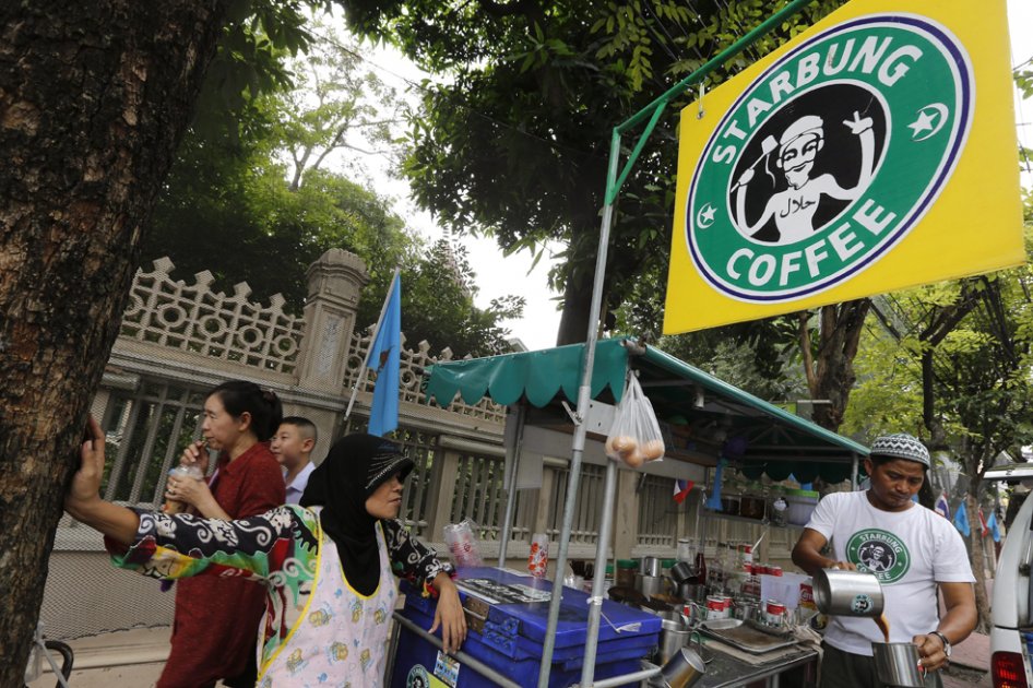 Damrong Maslae (dcha), de 44 años, sirve café en su puesto en la carretera de Phra Athit en Bangkok (Tailandia). Maslae se niega a retirar el logotipo "Starbung" de su puesto de café a pesar de la demanda interpuesta por la multinacional Starbucks por el parecido que tiene con su logotipo a pesar de que en 2012 un mandato judicial le obligaba a retirarlo. / EFE