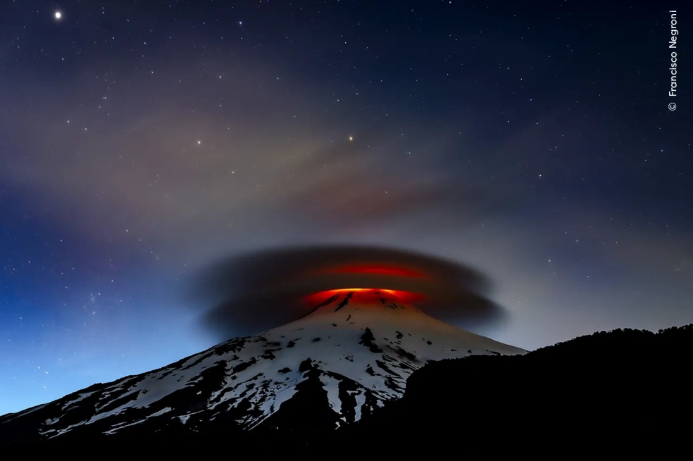 Francisco Negroni, de Chile, recibió una mención honorífica por “Tierra y cielo”. Según dice, en su fotografía se ve "una doble nube lenticular que se ilumina al anochecer por la lava emitida por el volcán Villarrica, Chile".