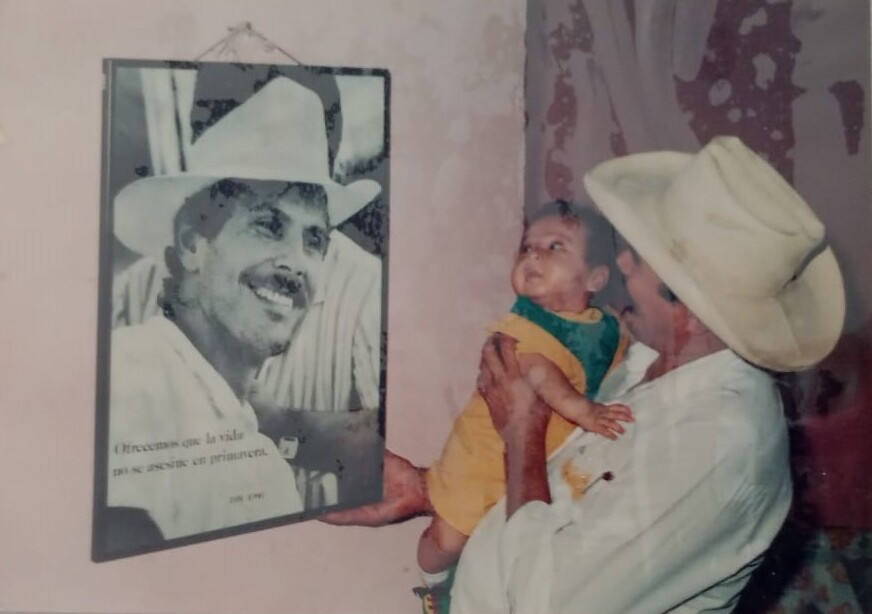 Chalitas y su hijo Marco Antonio frente a un retrato de Carlos Pizarro.