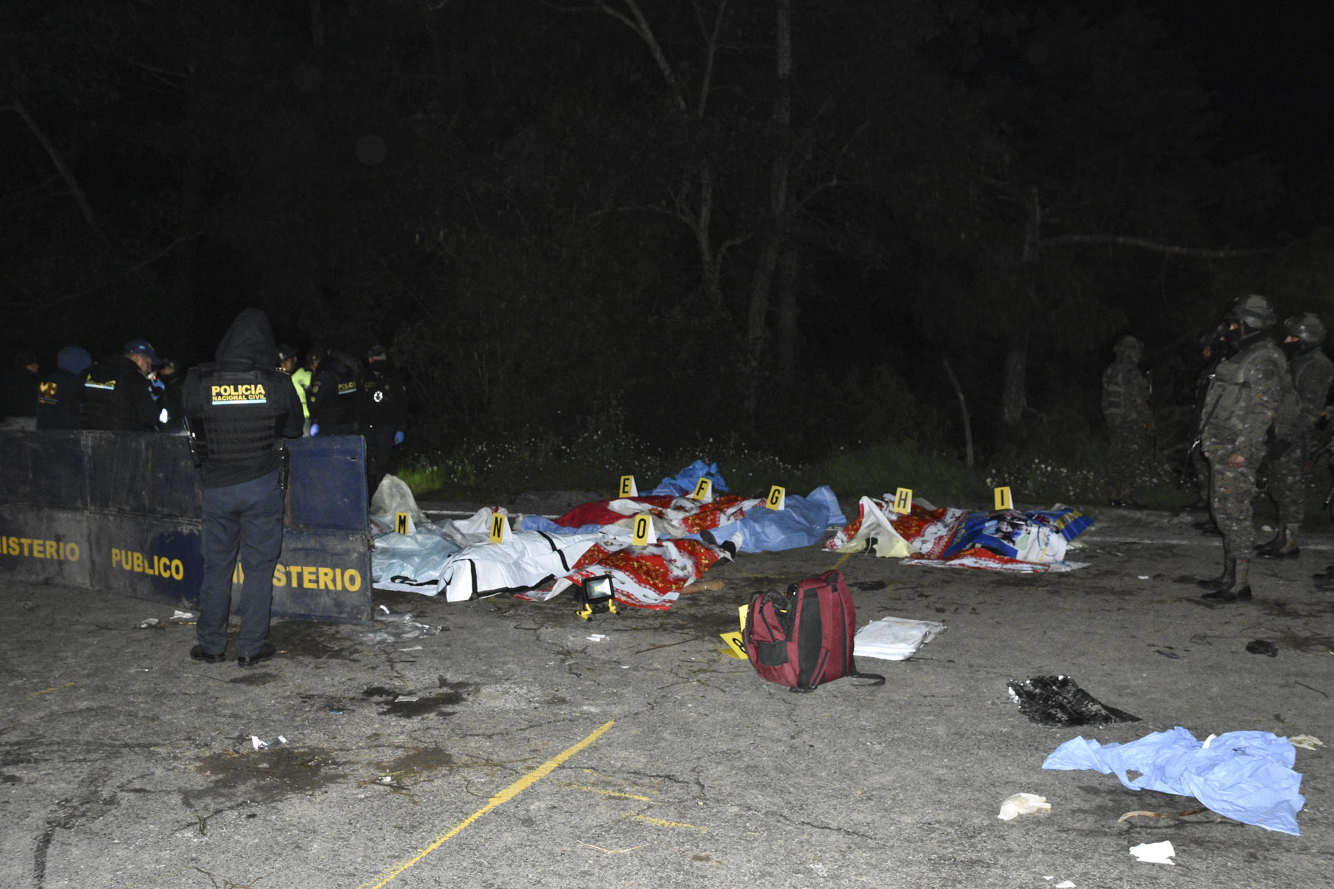 NAHUALÁ (GUATEMALA) 27/12/2025.- Miembros de las fuerzas de seguridad guatemaltecas vigilan junto a un grupo de víctimas después de que al menos quince personas murieran en la noche del viernes y otras diecinueve resultaran heridas durante un accidente de un bus de transporte público en el oeste de Guatemala, según confirmaron este sábado los cuerpos de socorro. EFE/ Fernando Estrada