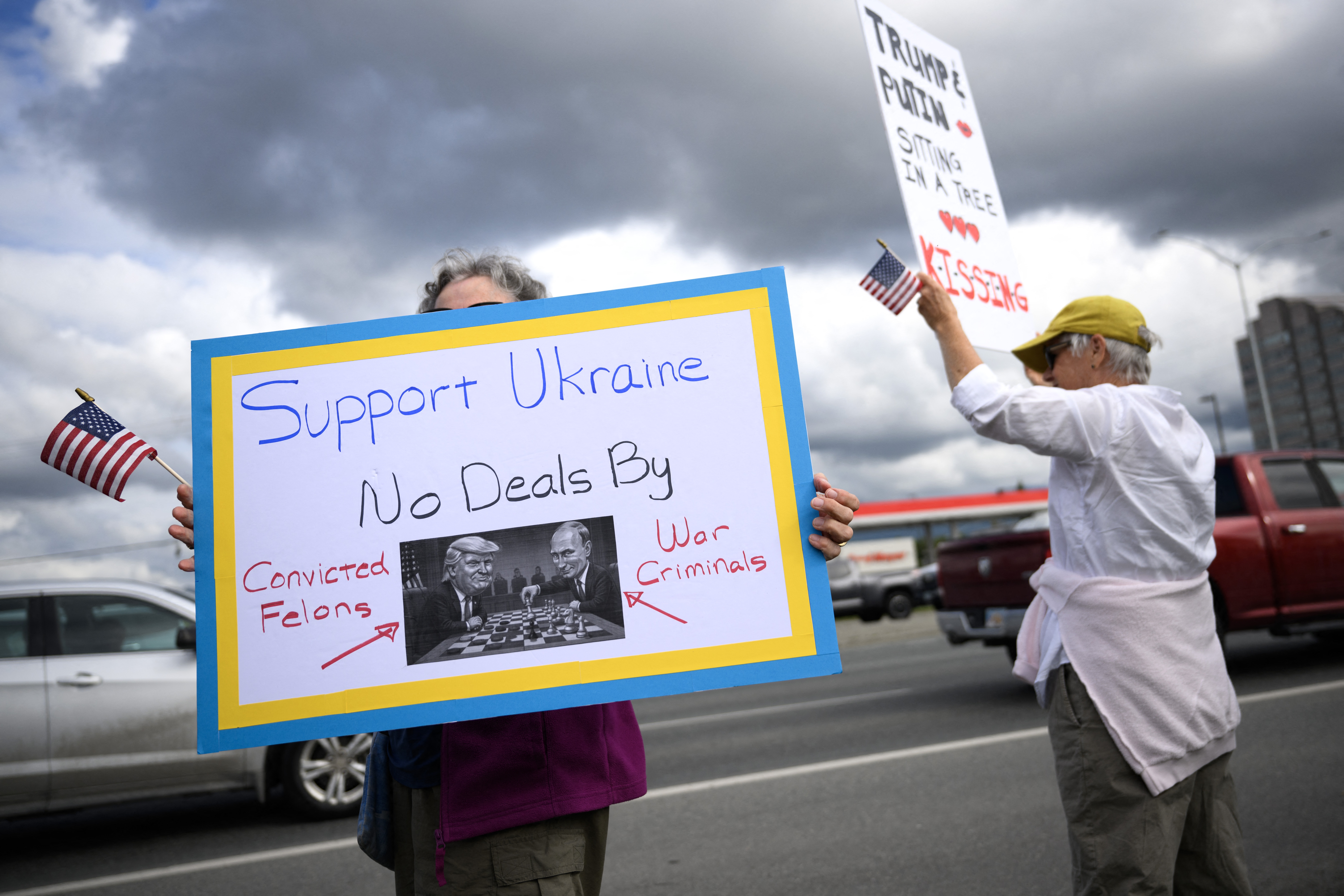 Manifestantes ondearon banderas y sostuvieron carteles mientras expresaron su apoyo a Ucrania a lo largo de la autopista Seward de Anchorage, Alaska, ante la reunión de Trump y Putin. En la foto sale una mujer con una pancarta en la que se lee: "No a los acuerdos con un delincuente convicto y con un criminal de guerra", aludiendo al republicano y al líder del Kremlin, respectivamente.