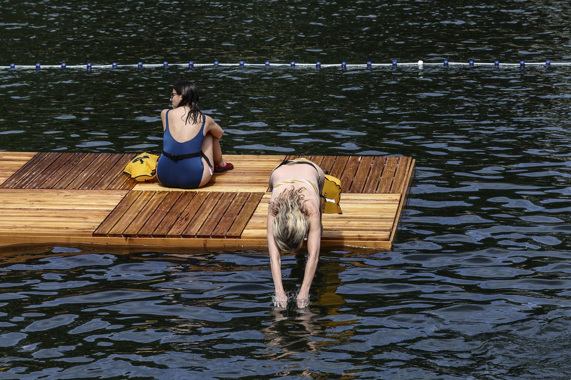 Paris (France), 05/07/2025.- A woman jumps into the water at the Pont Grenelle spot near of the Eiffel Tower, one of the three safe swimming areas that opened to the public on the Seine River, in Paris, France, 05 July 2025. From 05 July to 31 August 2025, people will be able to swim in three safe swimming areas on the Seine river, an activity that has been banned since 1923. (Francia) EFE/EPA/TERESA SUAREZ