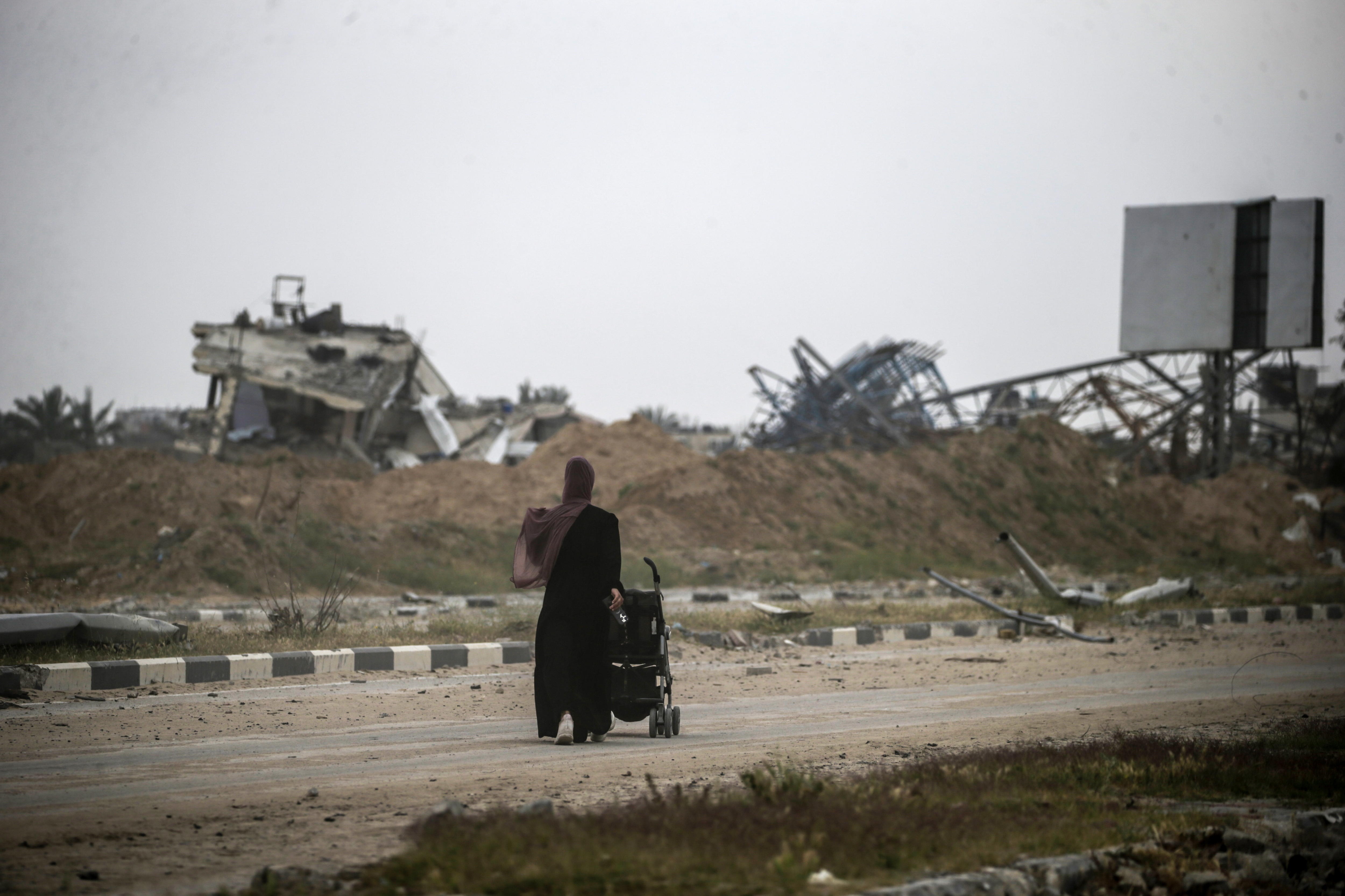 Una madre palestina empuja un cochecito con su bebé entre los escombros de los edificios destruidos tras la operación militar israelí en Jan Yunis, al sur de la Franja de Gaza, el 08 de abril de 2024.