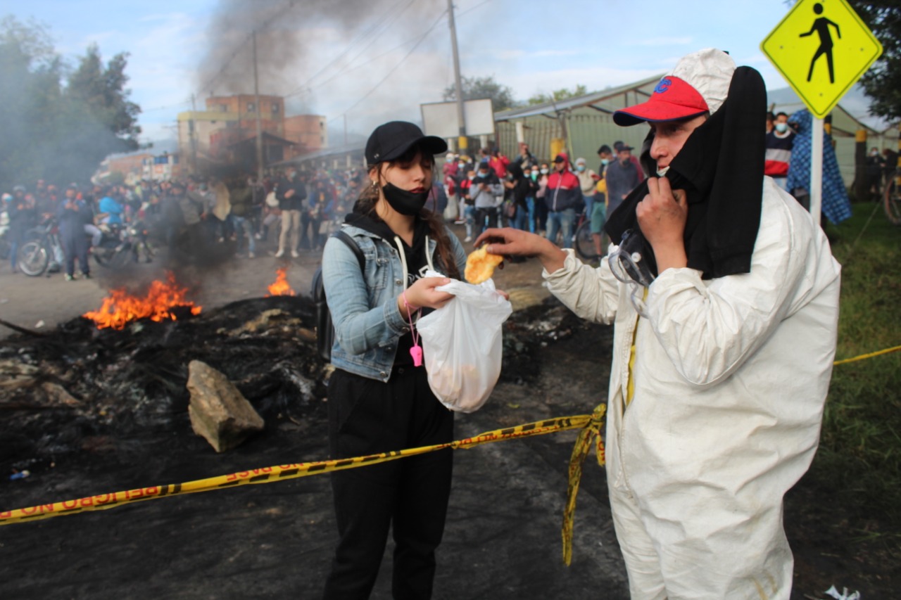 Una mujer le entrega un pan a un hombre detrás de una cinta de no pase