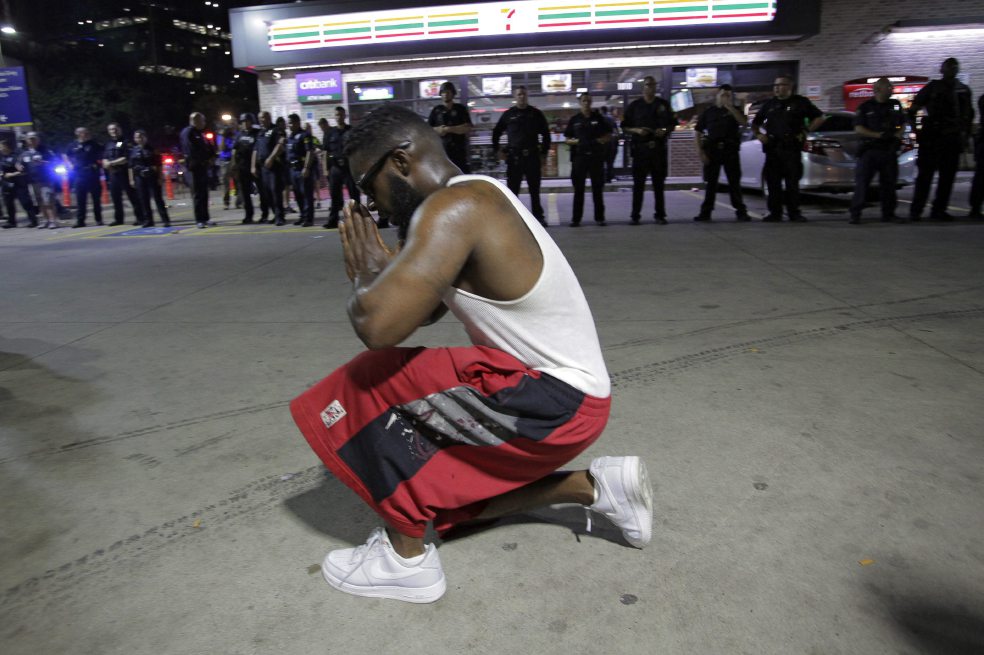 Un joven afroamericano se arrodilla frente a los policías tras el asesinato de cinco uniformados durante una marcha en Dallas. / EFE
