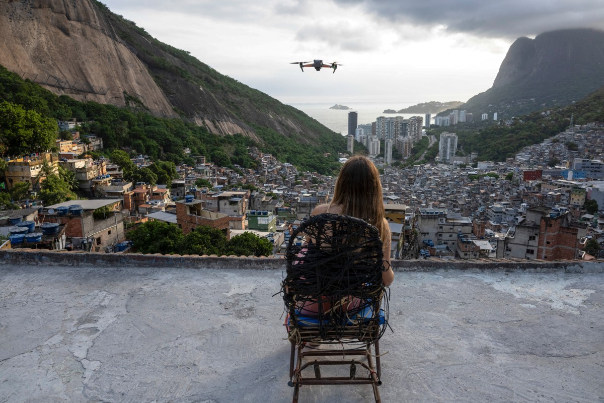 TOPSHOT - A woman is filmed by a drone for a social media video at the famous "Porta do Ceu" (Door to Heaven) tourist viewpoint in the Rocinha favela in Rio de Janeiro, Brazil, on March 5, 2026.