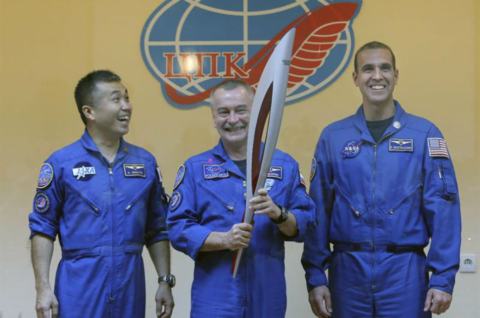 Los miembros de la misión de la Estación Espacial Internacional el japonés Koichi Wakata, el cosmonauta Mijail Tyurin y el astronauta estadounidense Rick Mastracchio, posan con la antorcha olímpica que viajará en la Soyuz a la EEI.
