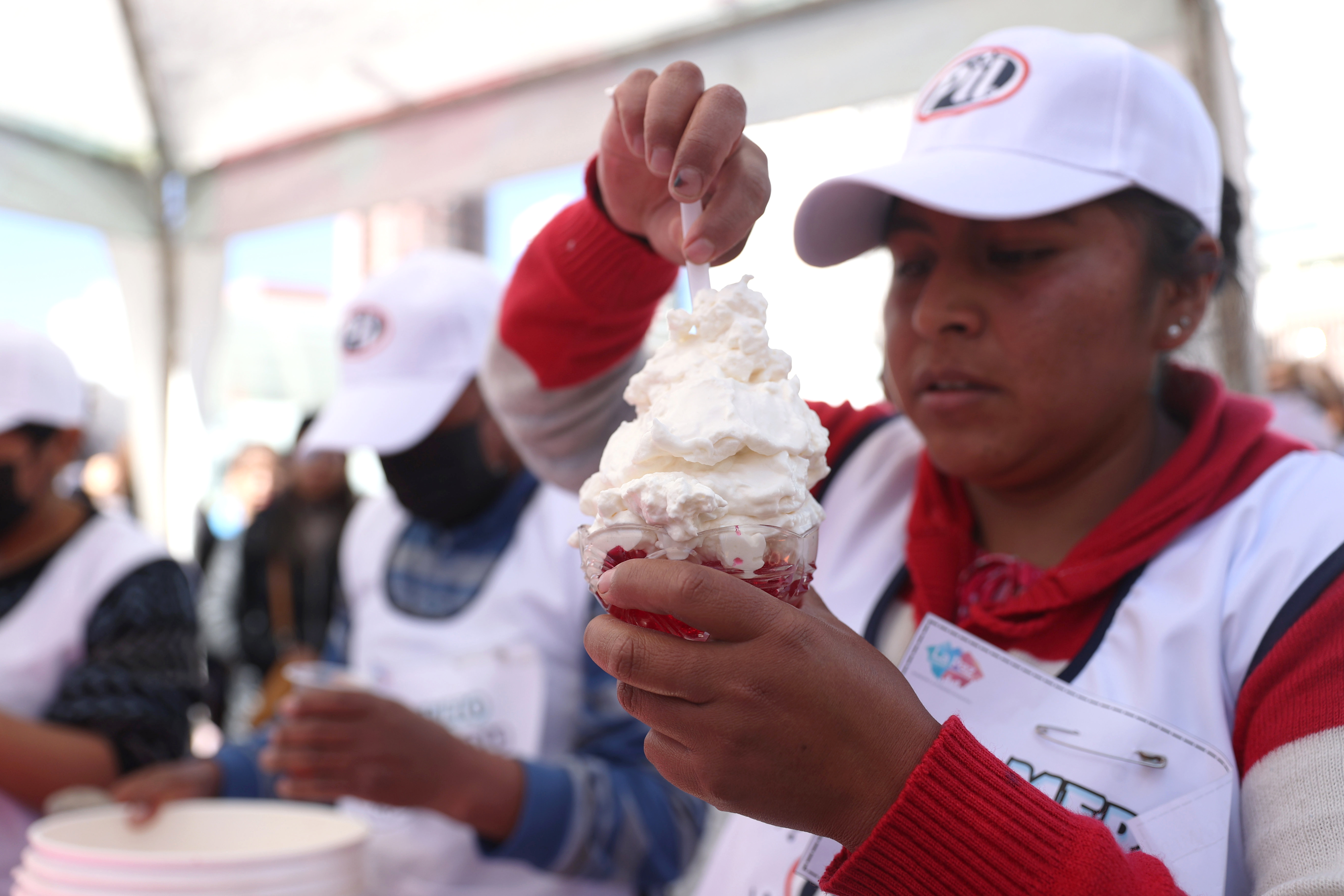 AME4380. LA PAZ (BOLIVIA), 24/07/2024.- Una mujer prepara crema chantillí durante una actividad gastronómica realizada este miércoles en La Paz (Bolivia). Una "guerra" de crema chantillí enfrentó este miércoles a vendedoras de la ciudad de La Paz, sede del Gobierno de Bolivia, en un concurso de sabores en el que se realzó al postre que fue adoptado de Francia hace décadas. EFE/Luis Gandarillas
