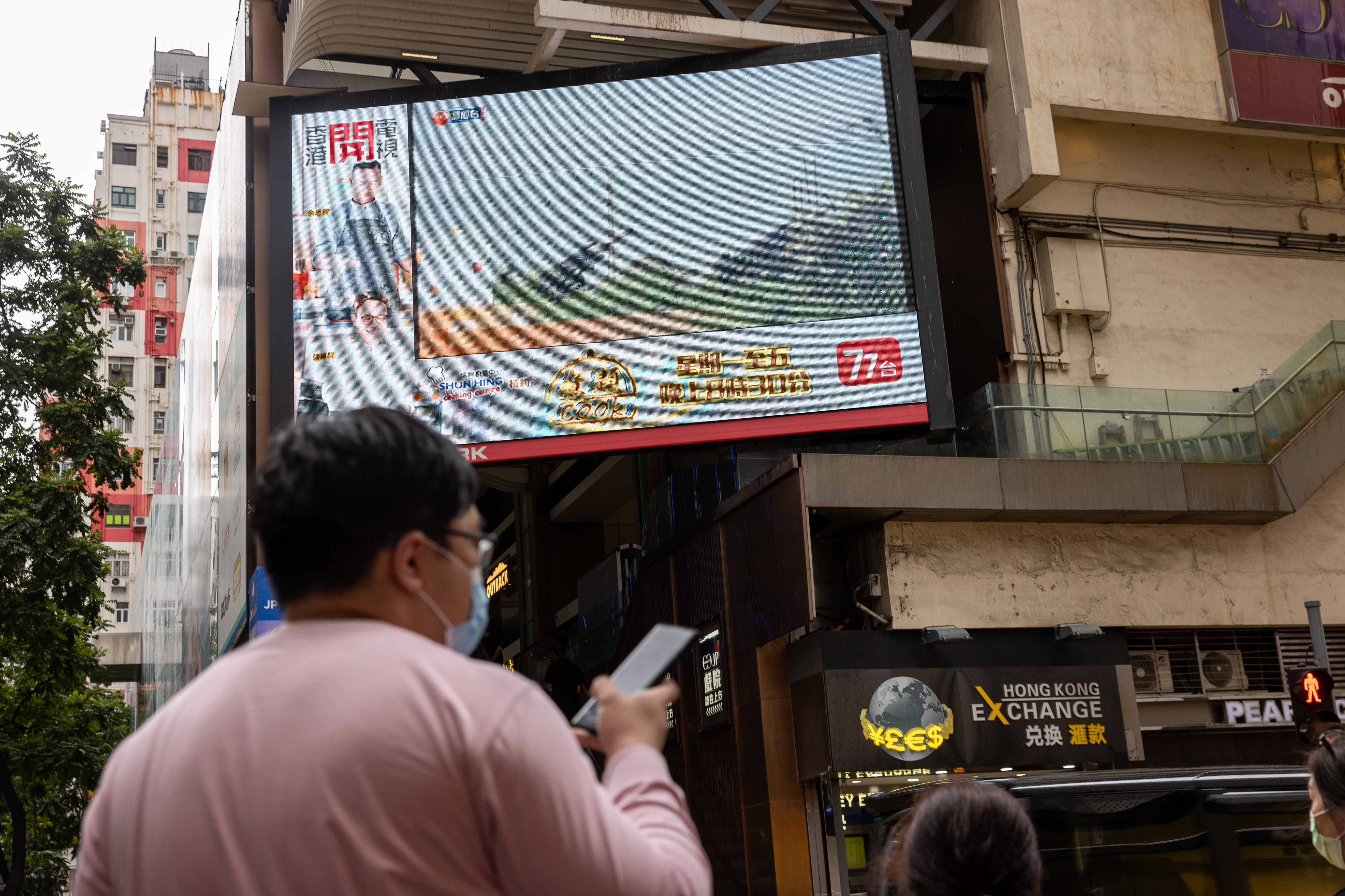 Hong Kong (China), 09/08/2022.- Pedestrians walk at a street past a large TV-screen displaying news broadcasting of Taiwanese army artillery pieces during a live-fire drill, in Hong Kong, China, 09 August 2022. Beijing has announced its navy and air force would continue joint live-fire drills in the waters and airspace around Taiwan. (Incendio) EFE/EPA/JEROME FAVRE