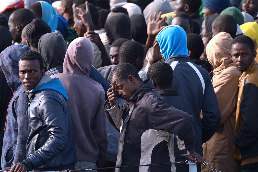 Un grupo de migrantes rescatados en el Mediterráneo espera desembarcar en el puerto de Sicilia, Italia. /AFP