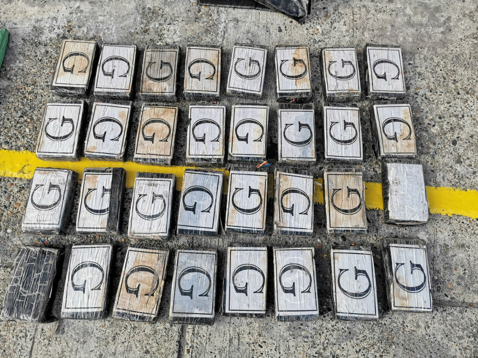 Treinta y dos paquetes rectangulares con cocaína en su interior. Casa uno tiene la letra G impresa.