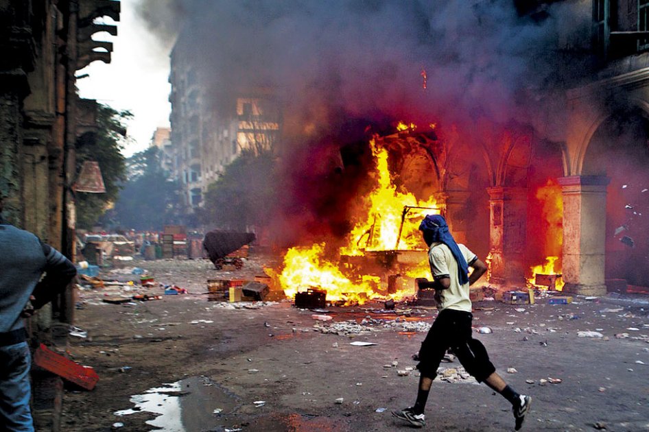 Un seguidor del presidente derrocado, Mohamed Mursi, pasa frente a un vehículo quemado en la plaza Ramses en El Cairo, uno de los epicentros de las protestas y la represión del ejército. / AFP