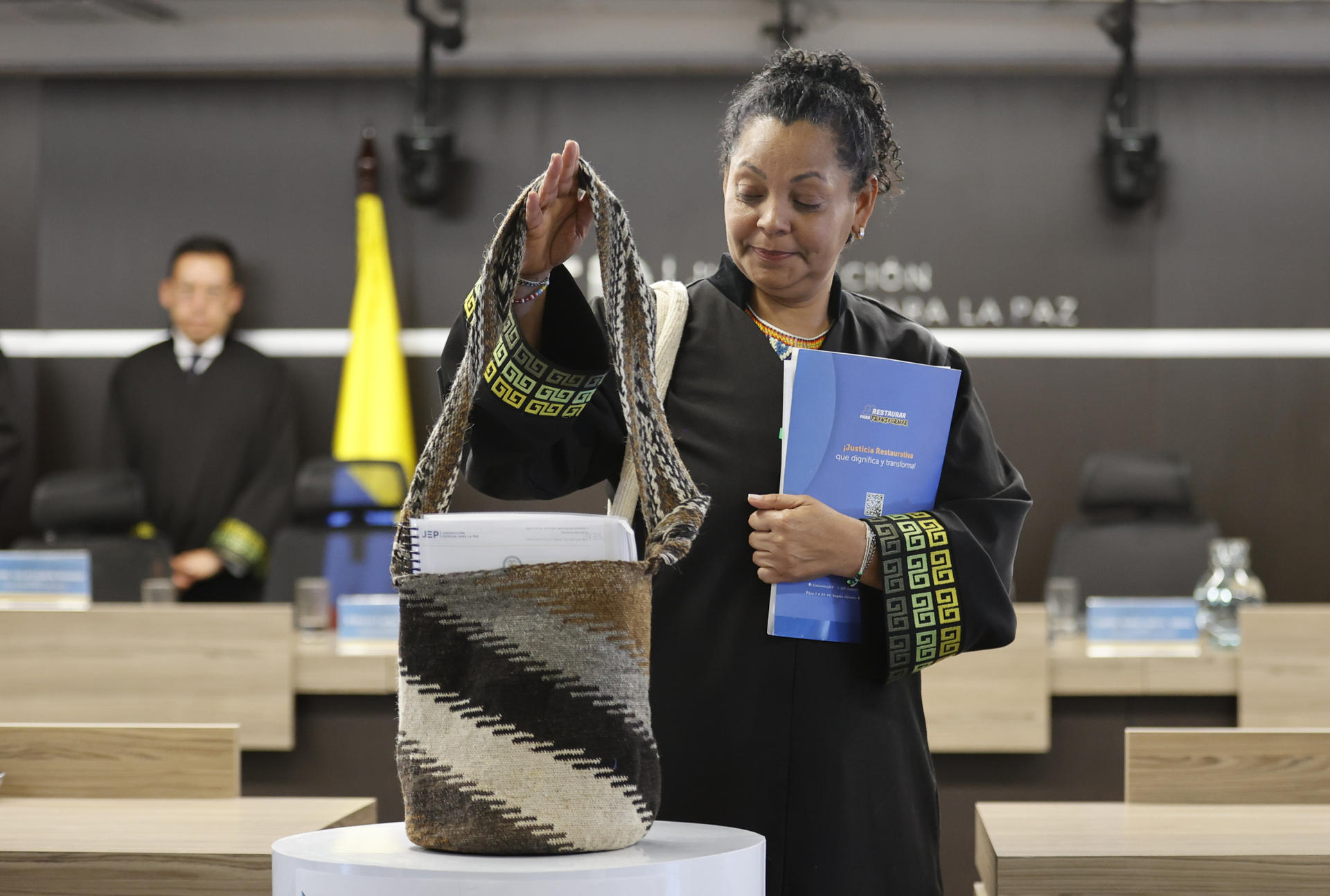 AME641. BOGOTÁ (COLOMBIA), 18/09/2025.- La presidenta de la Sección de Primera Instancia para Casos de Reconocimiento de Verdad y Responsabilidad, la magistrada Ana Manuela Ochoa Arias, sostiene una mochila kankuama a su llegada a una audiencia este jueves, en Bogotá (Colombia). La Jurisdicción Especial para la Paz (JEP) condenó a doce exmilitares colombianos a penas restaurativas de entre cinco y ocho años por crímenes de guerra y de lesa humanidad, como máximos responsables de 135 asesinatos cometidos en el norte del país entre 2002 y 2005, en el marco del conflicto armado. EFE/ Mauricio Dueñas Castañeda
