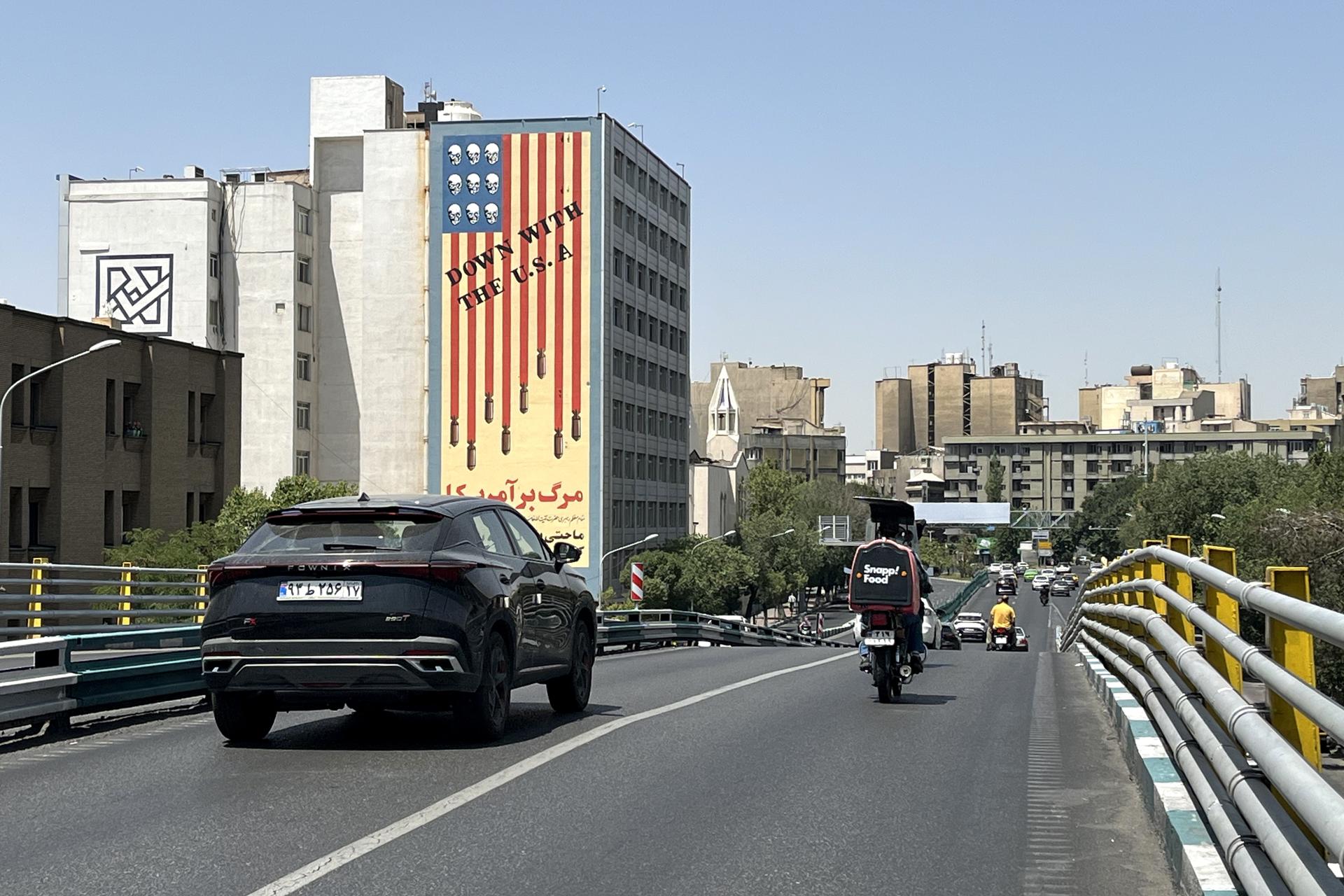 Tehran (Iran (Islamic Republic Of)), 22/06/2025.- Traffic passes by a building displaying an anti-US mural in Tehran, Iran, 22 June 2025. The US forces struck three of Iran's key nuclear sites: Natanz, Isfahan and Fordo, US President Trump announced on 21 June. Israel and Iran have been exchanging fire since Israel launched strikes across Iran on 13 June 2025 as part of Operation 'Rising Lion.' (Teherán) EFE/EPA/ABEDIN TAHERKENAREH