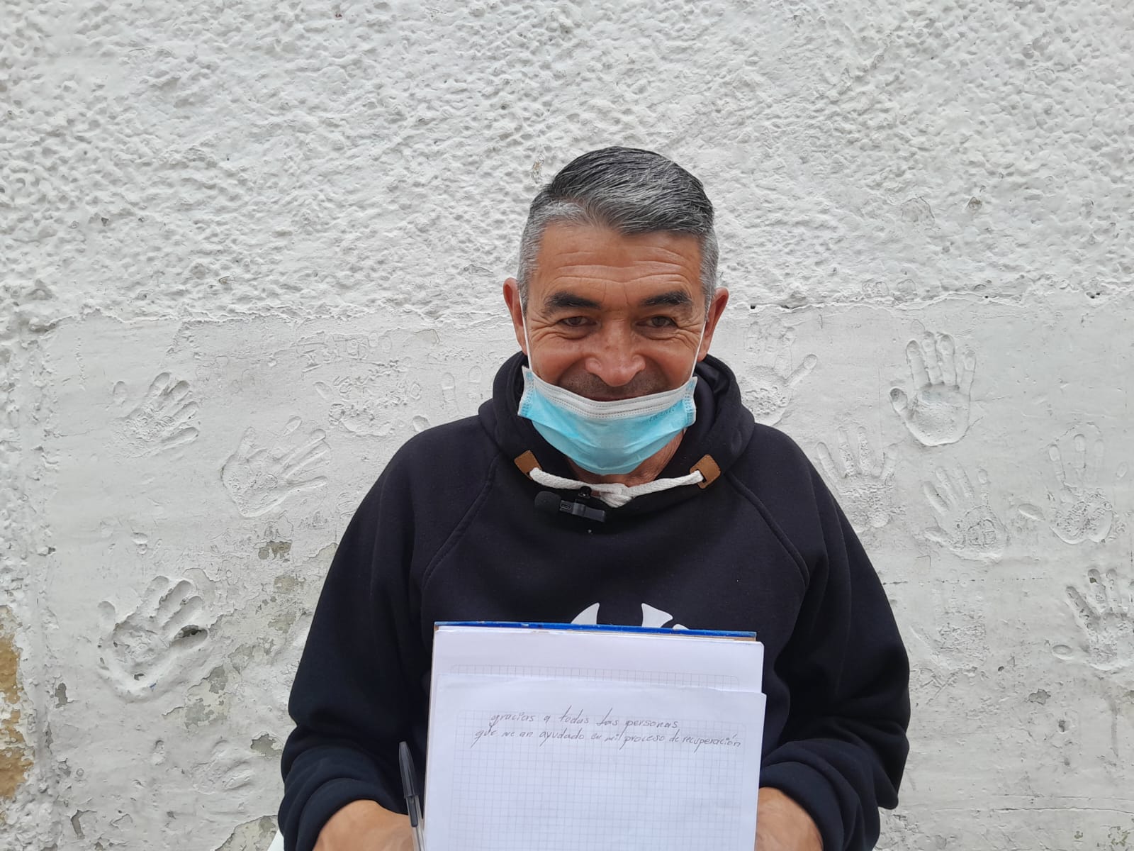 Víctor Manuel sosteniendo un cuaderno con la frase, "gracias a todas las personas que me han ayudado en mi proceso de recuperación".