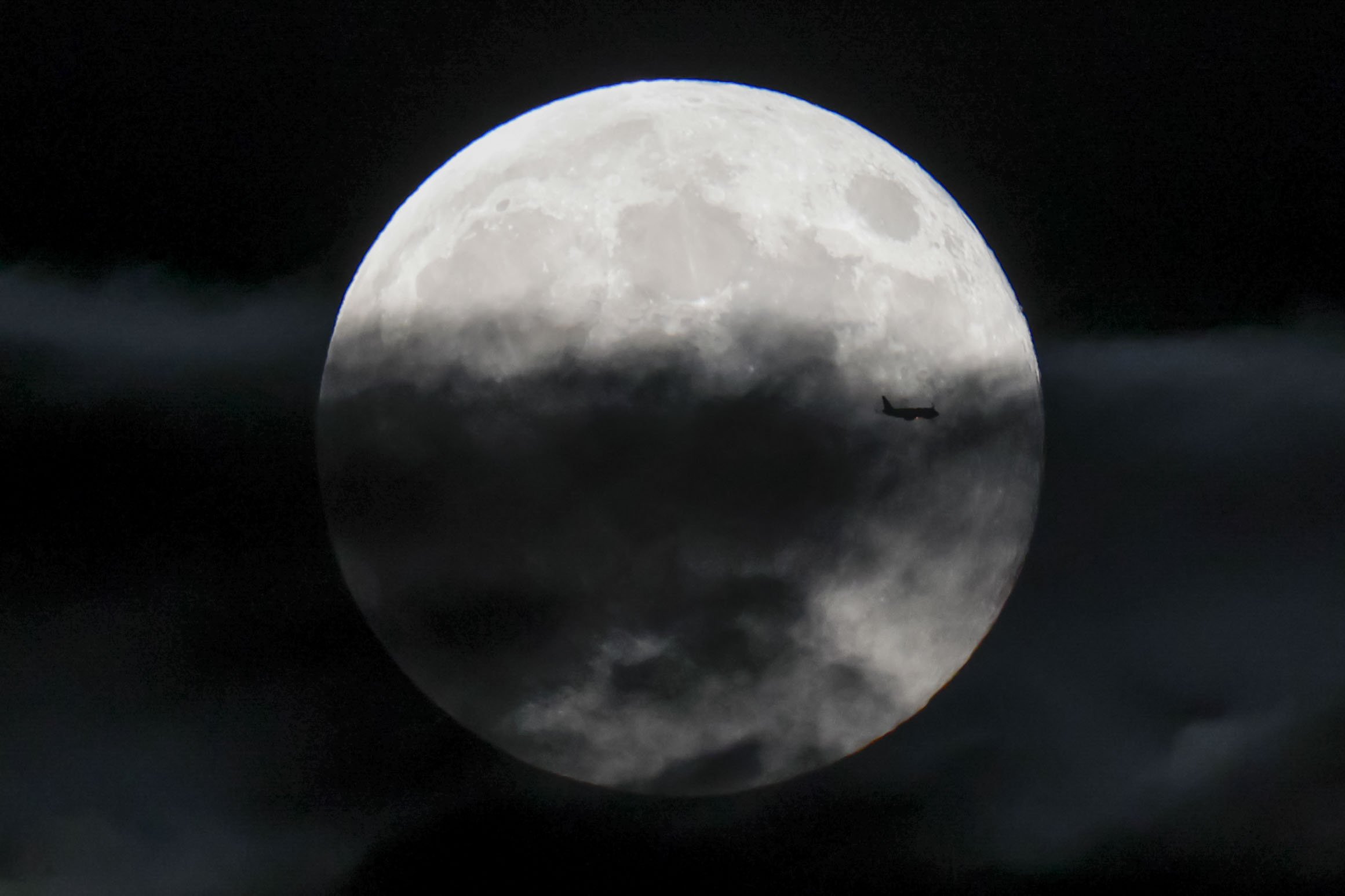 SANTIAGO DE COMPOSTELA, 17/10/2024.- La luna llena de este mes de octubre, conocida como la superluna del cazador, vista hoy jueves mientras pasa por delante un avión, desde Santiago de Compostela. EFE/Lavandeira Jr