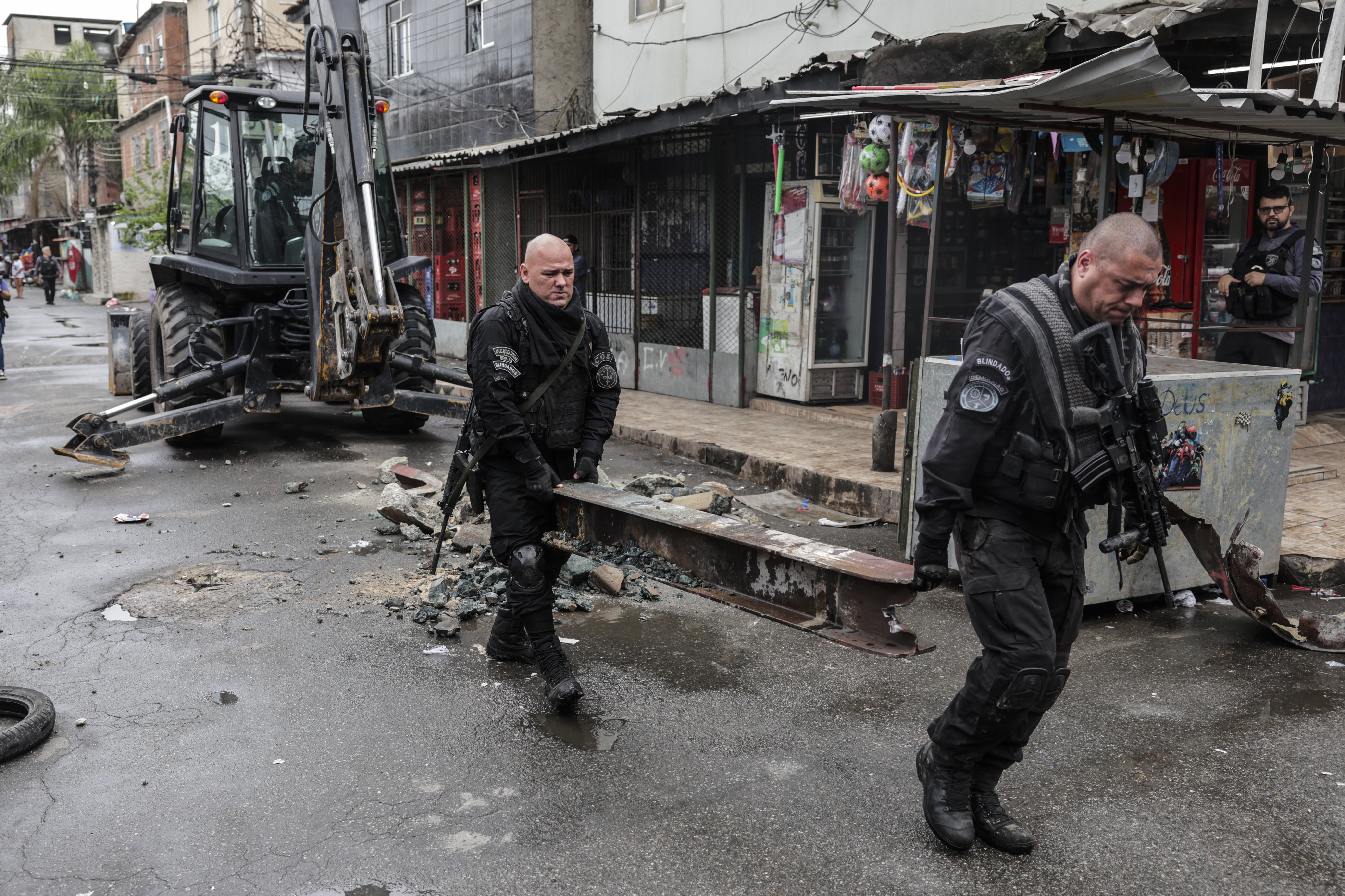 AME5609. RÍO DE JANEIRO (BRASIL), 09/10/2023.- Policías cargan una barra de refuerzo puesta por los narcotraficantes, durante un operativo contra las bandas criminales en una favela de la ciudad de Río de Janeiro (Brasil). Cerca de 1.000 policías fueron desplegados este lunes en tres de las favelas más violentas de Río de Janeiro en un megaoperativo con el que las autoridades buscan atrapar a cabecillas del Comando Vermelho, una de las organizaciones criminales más peligrosas de Brasil, informaron fuentes oficiales. Las acciones se desarrollan en el Complexo da Maré, Vila Cruzeiro y Cidade de Deus, donde los agentes buscan cumplir 100 órdenes de captura, según dijo en una rueda de prensa el secretario de la Policía Civil del estado de Río de Janeiro, José Renato Torres. EFE/ Antonio Lacerda
