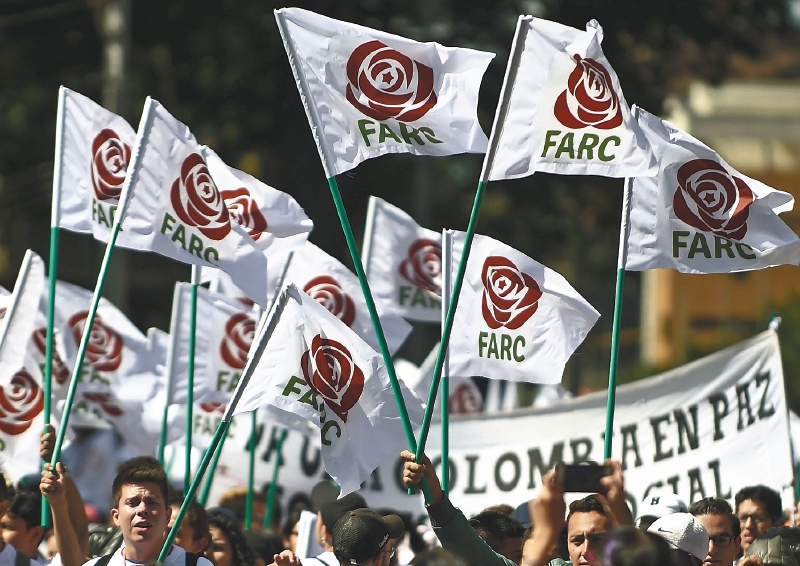 Foto de archivo que muestra a miembros y simpatizantes de las FARC con banderas con el nuevo logo de la rebautizada FARC (Fuerza Alternativa Revolucionaria del Común), transformada en partido político tras su desarme, durante la clausura de su Congreso Nacional en Bogotá el 1 de septiembre de 2017. / AFP / Raul Arboleda