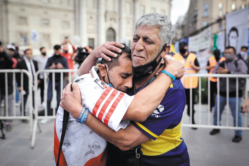 Un aficionado con la camiseta del Boca Juniors y otro con la camiseta del River Plate, se abrazan luego de despedir los restos de Diego Armando Maradona en el velatorio de la capital bonaerense, hoy jueves en la Plaza de Mayo.- EFE/Juan Ignacio Ronconori
