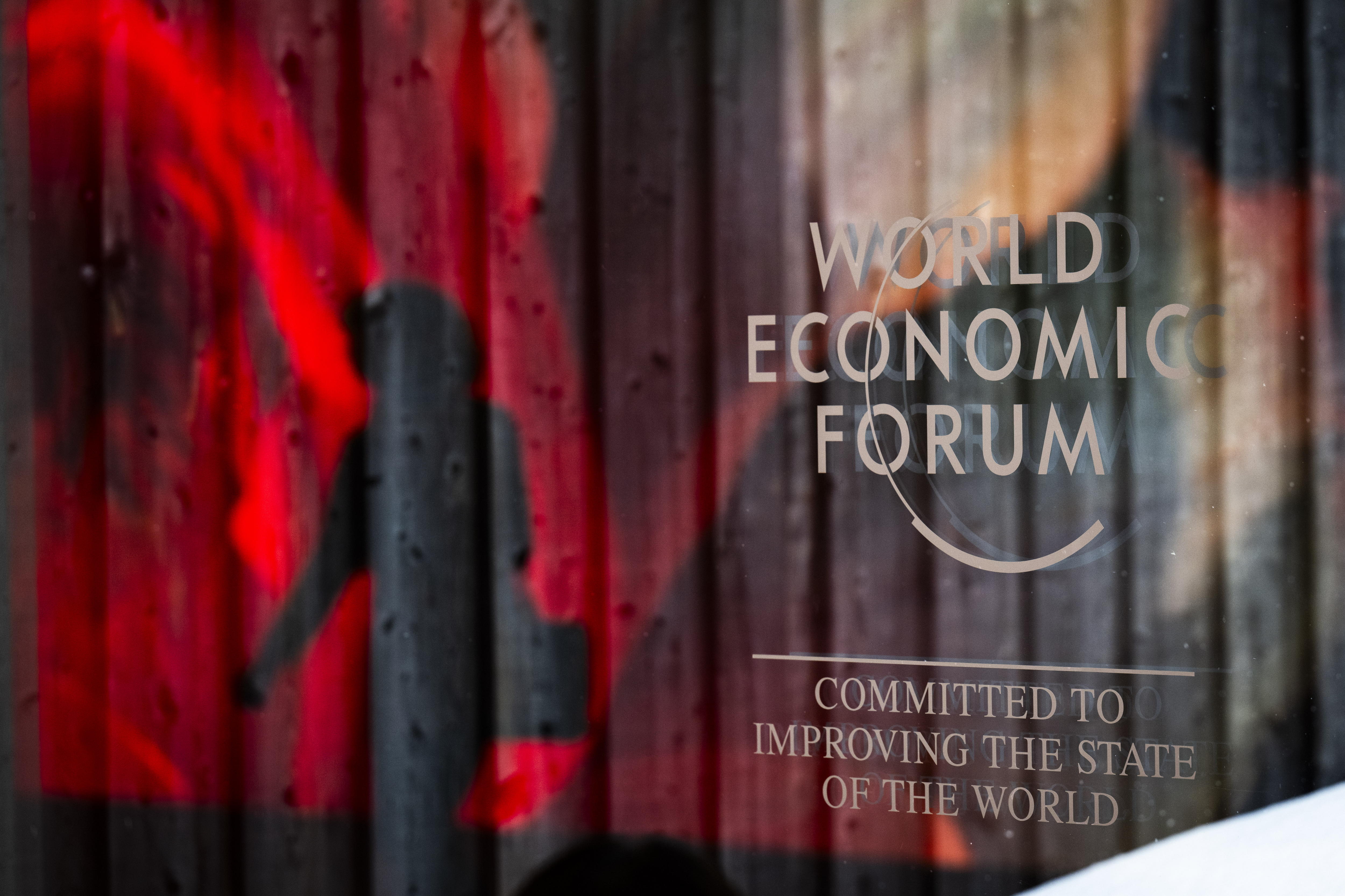 Davos (Switzerland Schweiz Suisse), 19/01/2024.- The logo of the WEF and a reflection of an AI generated projection are pictured as a woman passes by on the closing day of the 54th annual meeting of the World Economic Forum (WEF) in Davos, Switzerland, 19 January 2024. The meeting brings together entrepreneurs, scientists, corporate and political leaders in Davos under the topic 'Rebuilding Trust' from 15 to 19 January. (Suiza) EFE/EPA/GIAN EHRENZELLER