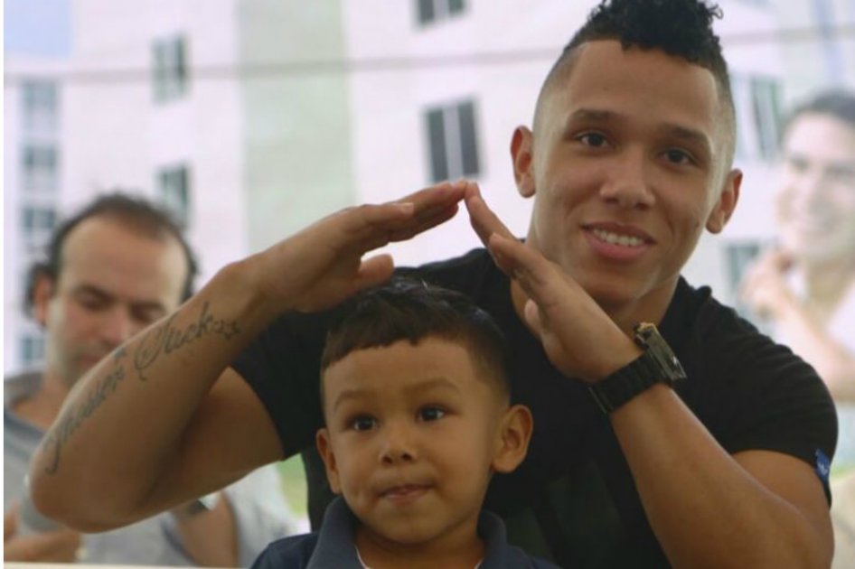 El pesista junto a su hijo al momento de recibir su casa. / @ViceColombia
