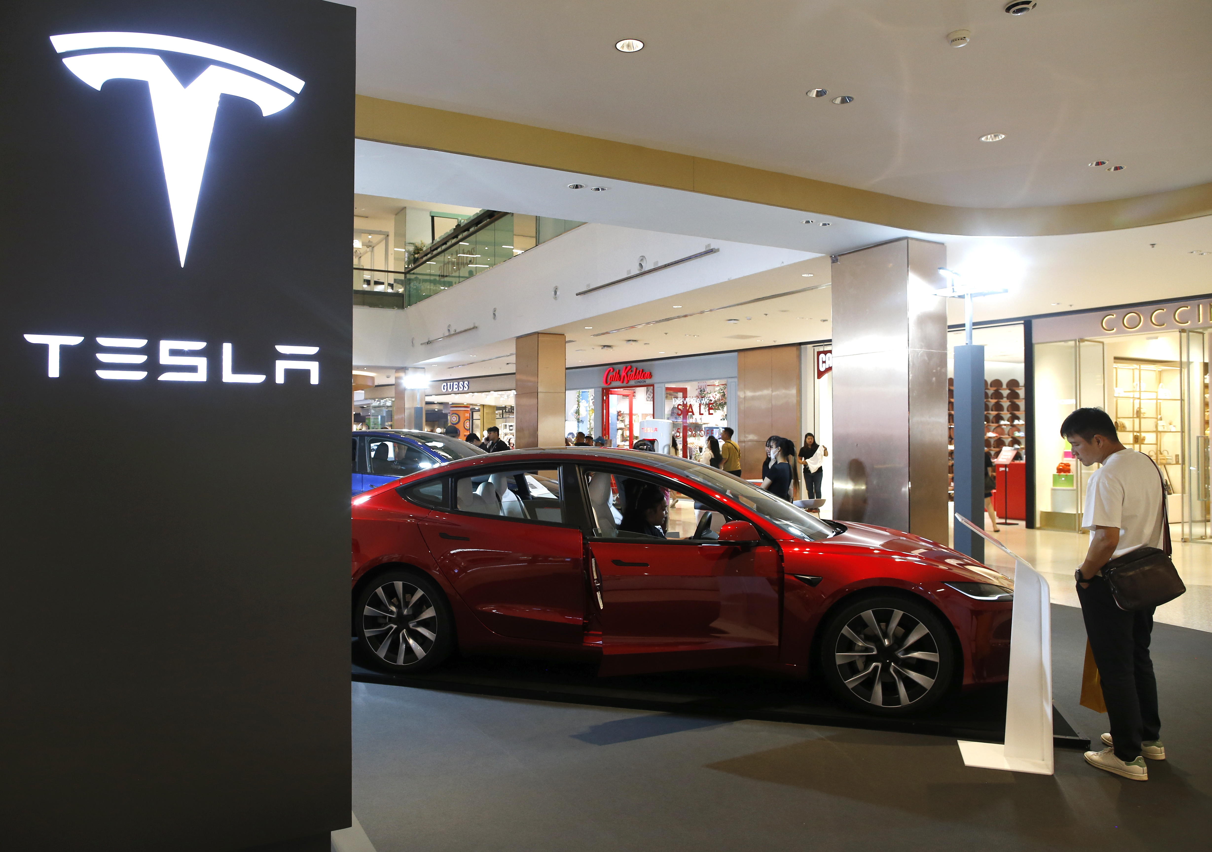 Bangkok (Thailand), 24/06/2024.- Visitors inspect a Tesla electric car displayed for sale at a shopping mall in Bangkok, Thailand, 24 June 2024. The US electric vehicle maker Tesla has launched a special rate program for Model 3 and Model Y in Thailand aimed at boosting its sales and compete with Chinese made electric vehicles. (Tailandia) EFE/EPA/RUNGROJ YONGRIT