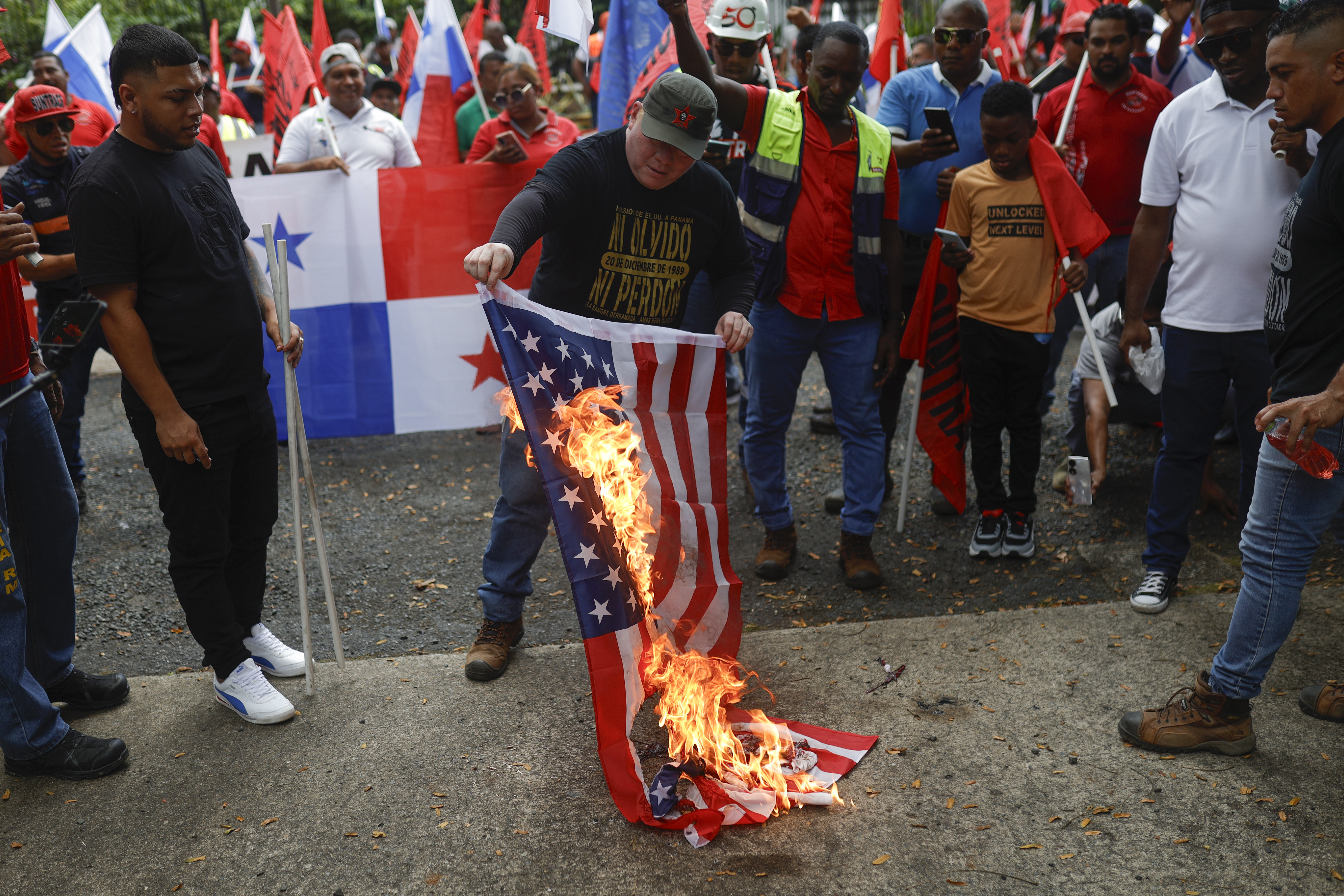AME2774. CIUDAD DE PANAMÁ (PANAMÁ), 20/01/2025.- Un hombre quema una bandera de los Estados Unidos en una protesta de sindicalistas contra el presidente electo de los Estados Unidos, Donald Trump, este lunes, afuera de la casa del embajador de los Estados Unidos en Panamá, en la Ciudad de Panamá (Panamá). Sindicalistas de Panamá protestaron contra Donald Trump "en el día de la toma de posesión de quien amenaza" la soberanía del país, en referencia a la arremetida del nuevo gobernante de EE.UU. contra la vía interoceánica. EFE/ Bienvenido Velasco