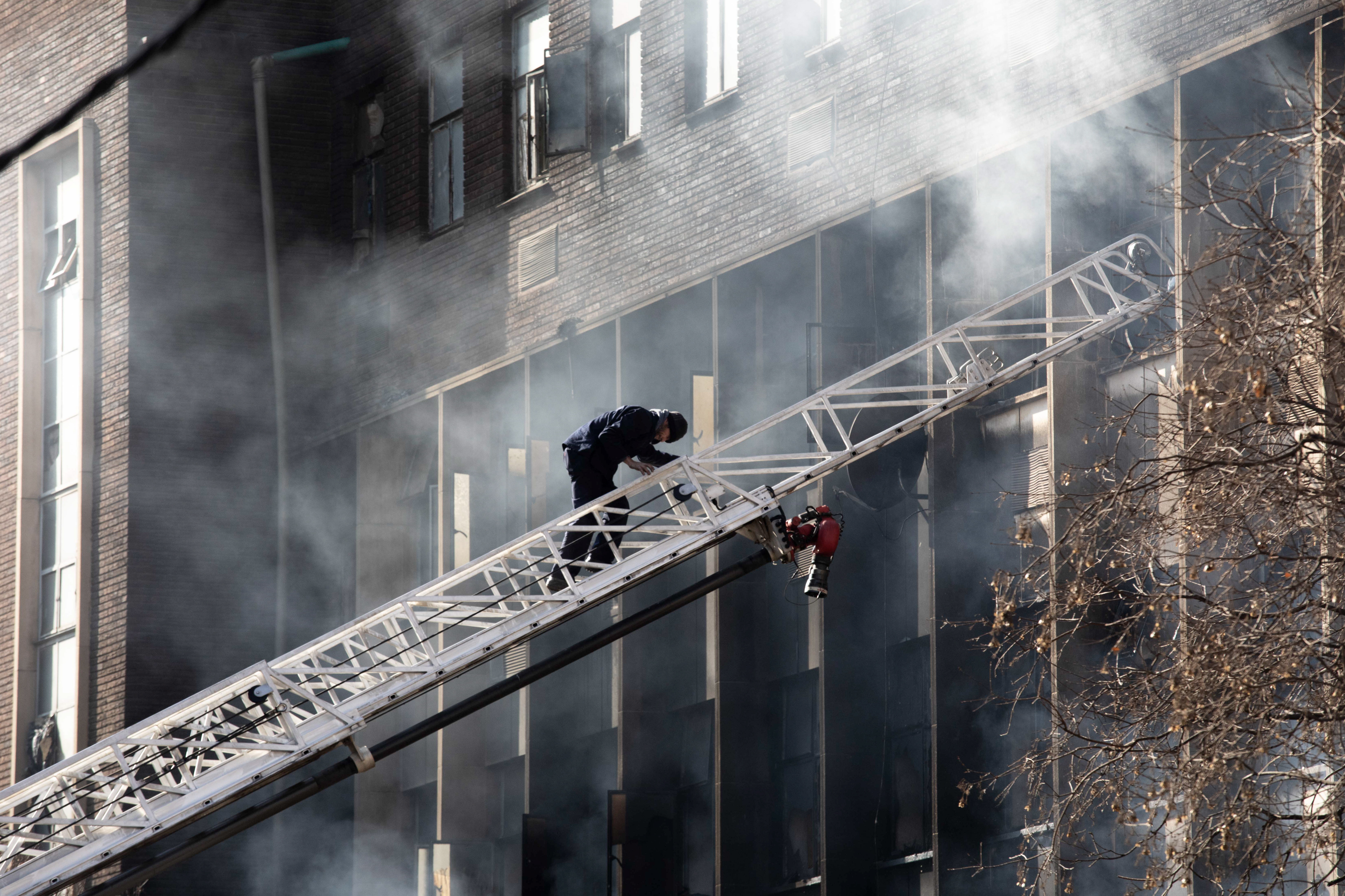 Johannesburg (South Africa), 31/08/2023.- An emergency services member climbs a ladder at the site of a fire that broke out at a five-storey building in the city centre, in Johannesburg, South Africa, 31 August 2023. More than 60 people have died following a fire that ravaged a building in central Johannesburg according to officials. (Sudáfrica, Johannesburgo) EFE/EPA/KIM LUDBROOK