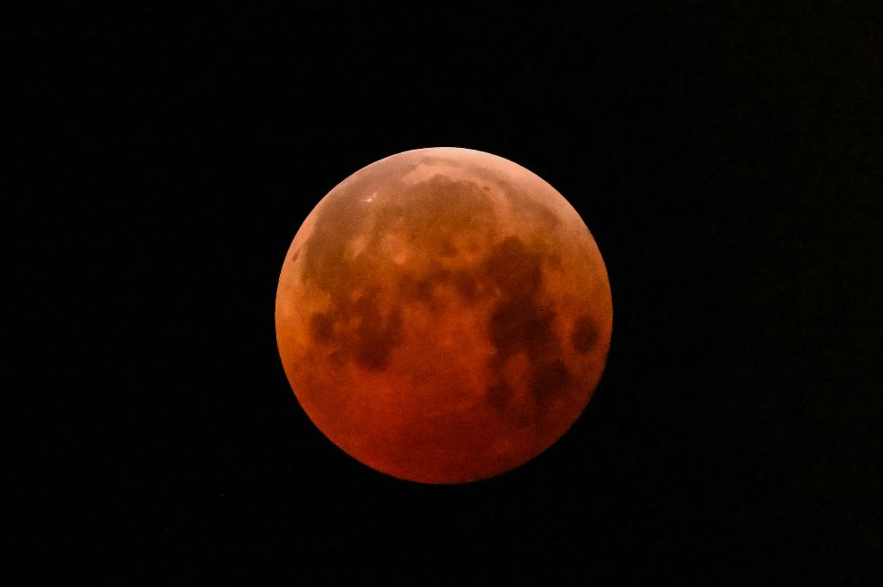 La NASA explica que durante un eclipse lunar, la Luna se ve roja o naranja porque toda la luz solar que no está bloqueada por nuestro planeta se filtra a través de una gruesa capa de la atmósfera terrestre en su camino hacia la superficie lunar.