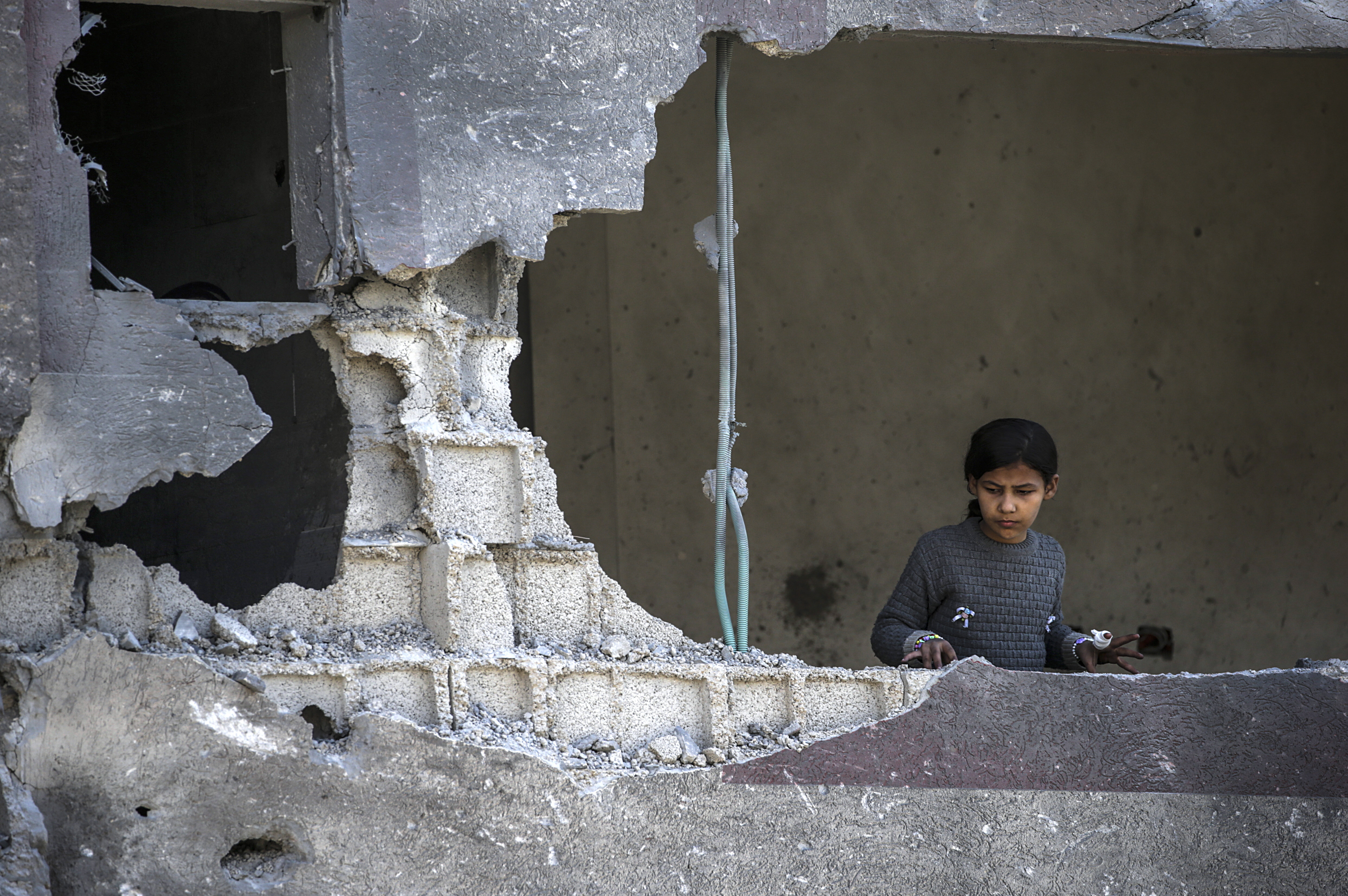Al Nusairat Southern Gaza Strip (-), 20/03/2024.- A Palestinian little girl looks out of a damaged building while others check for missing people under the rubble of a destroyed house following an Israeli air strike, in Al Nusairat refugee camp, southern Gaza Strip, 20 March 2024. More than 31,500 Palestinians and over 1,300 Israelis have been killed, according to the Palestinian Health Ministry and the Israel Defense Forces (IDF), since Hamas militants launched an attack against Israel from the Gaza Strip on 07 October 2023, and the Israeli operations in Gaza and the West Bank which followed it. EFE/EPA/MOHAMMED SABER